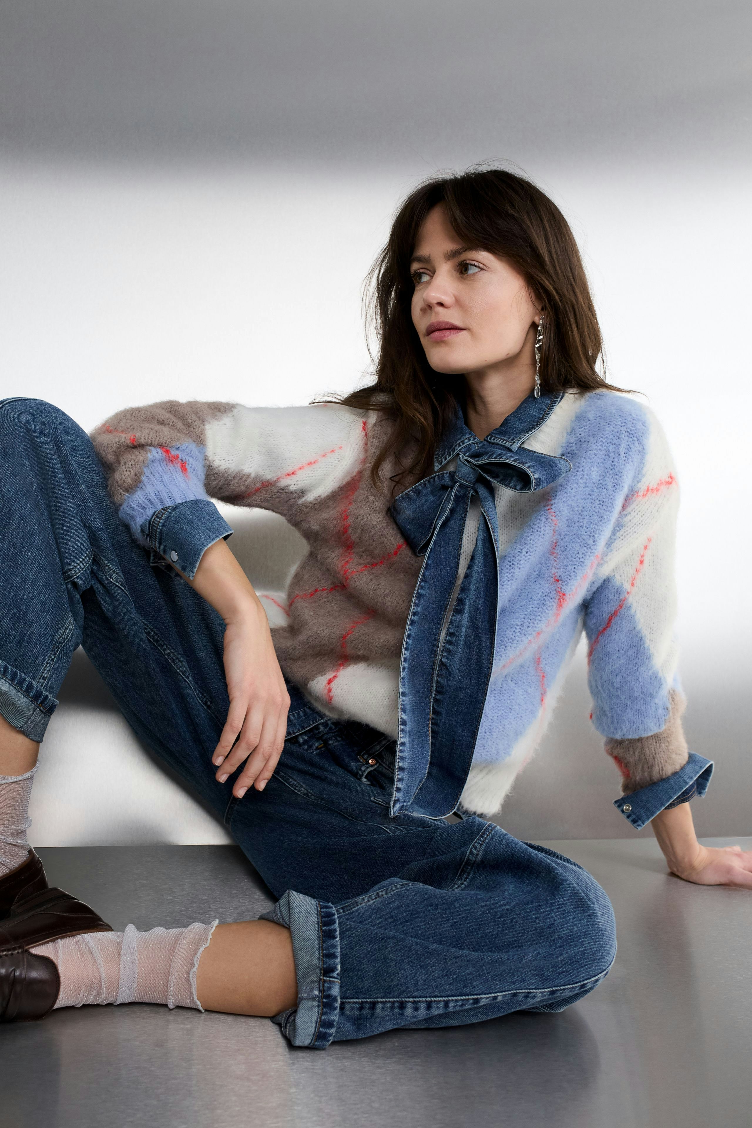 Casual women's jeans: A woman in relaxed-fit barrel jeans, paired with a red pullover and cap.