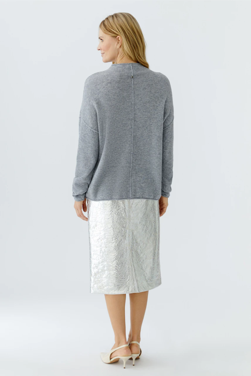 Casual women's pullover: A woman in a gray pullover paired with a shiny silver skirt.