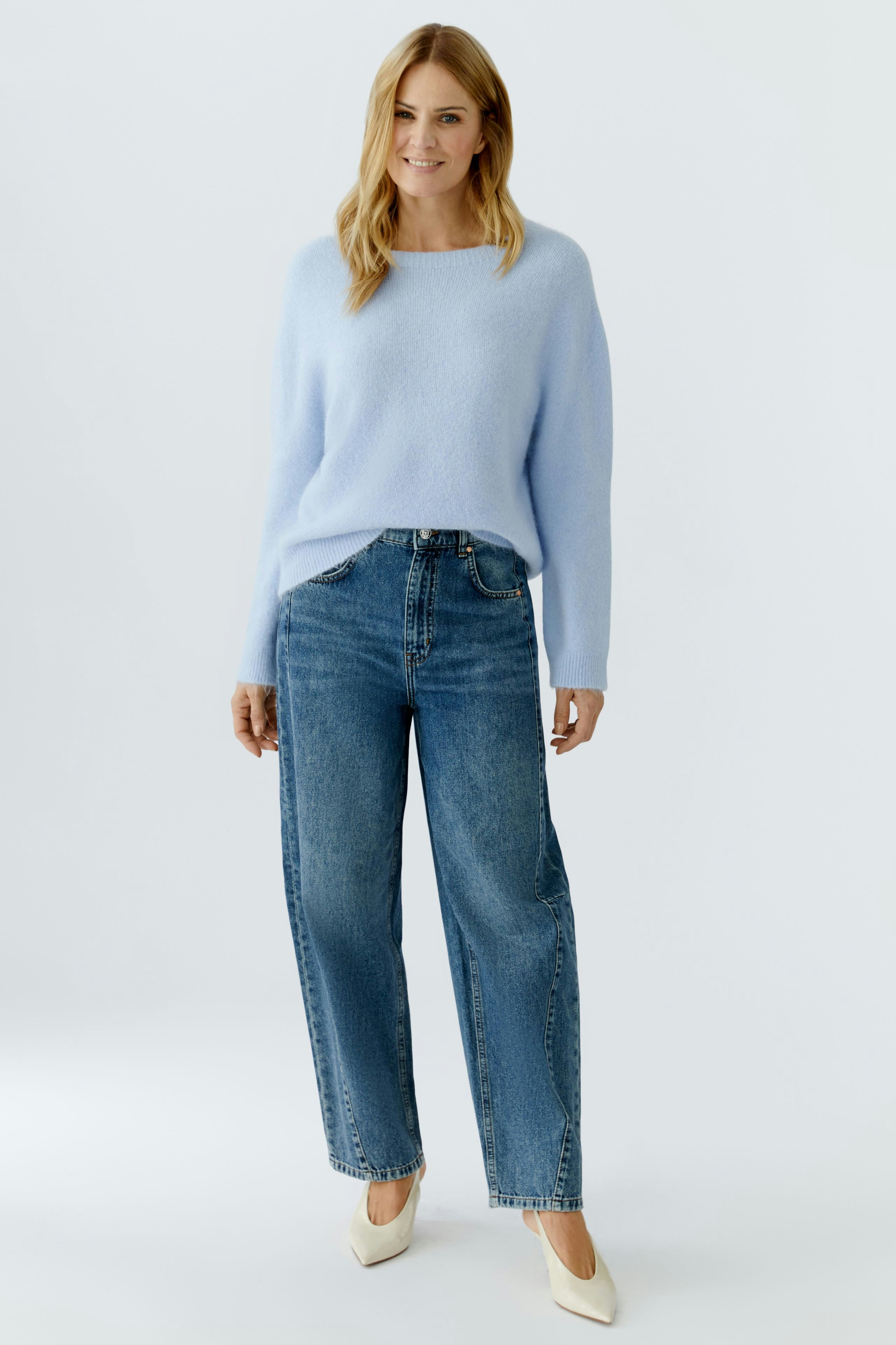 Casual women's pullover: Woman in a light blue pullover paired with high-waisted jeans.