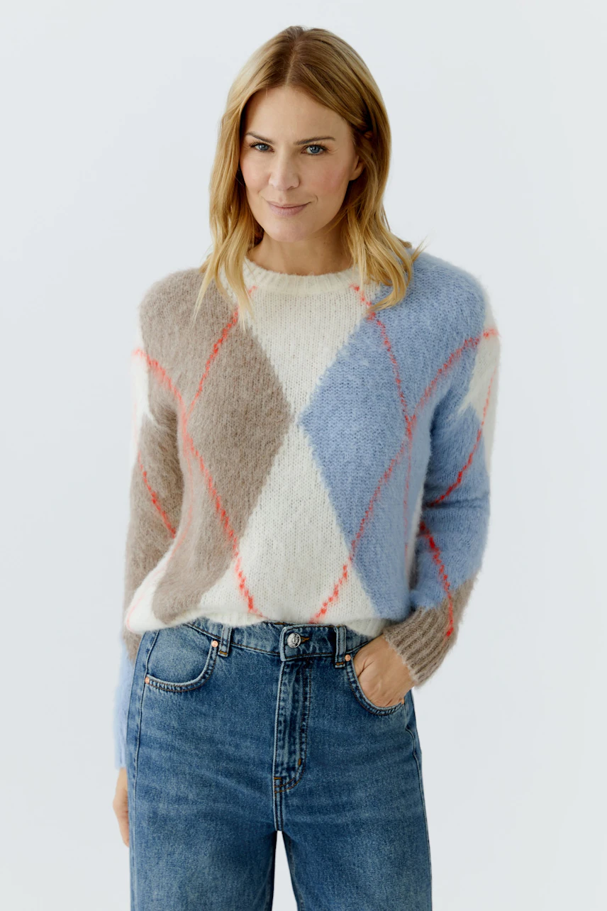 Casual women's pullover: Woman in a cozy, multicolored pullover with a diamond pattern and relaxed fit.