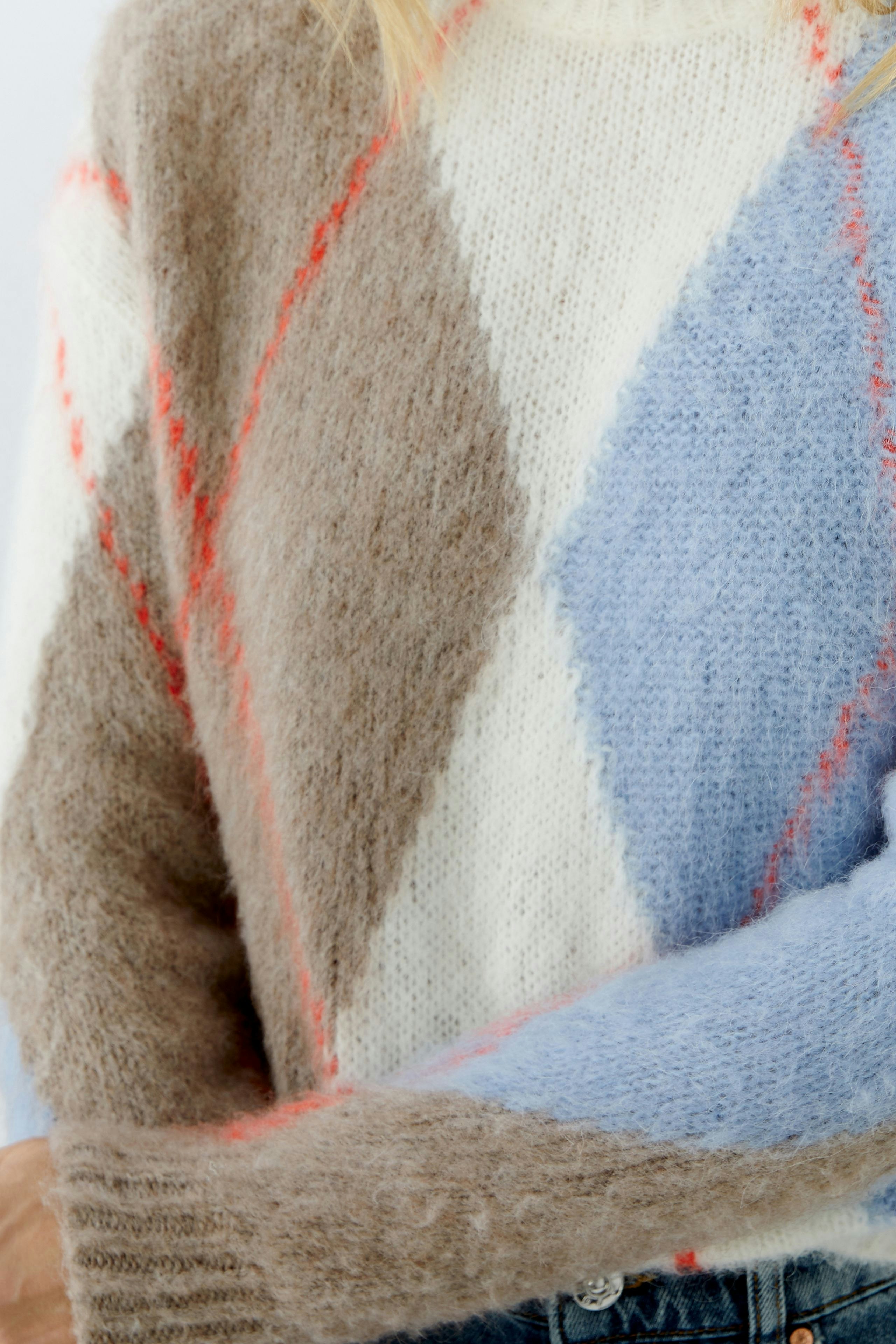 Cozy women's pullover: A woman in a soft, colorful knit pullover with a diamond pattern.