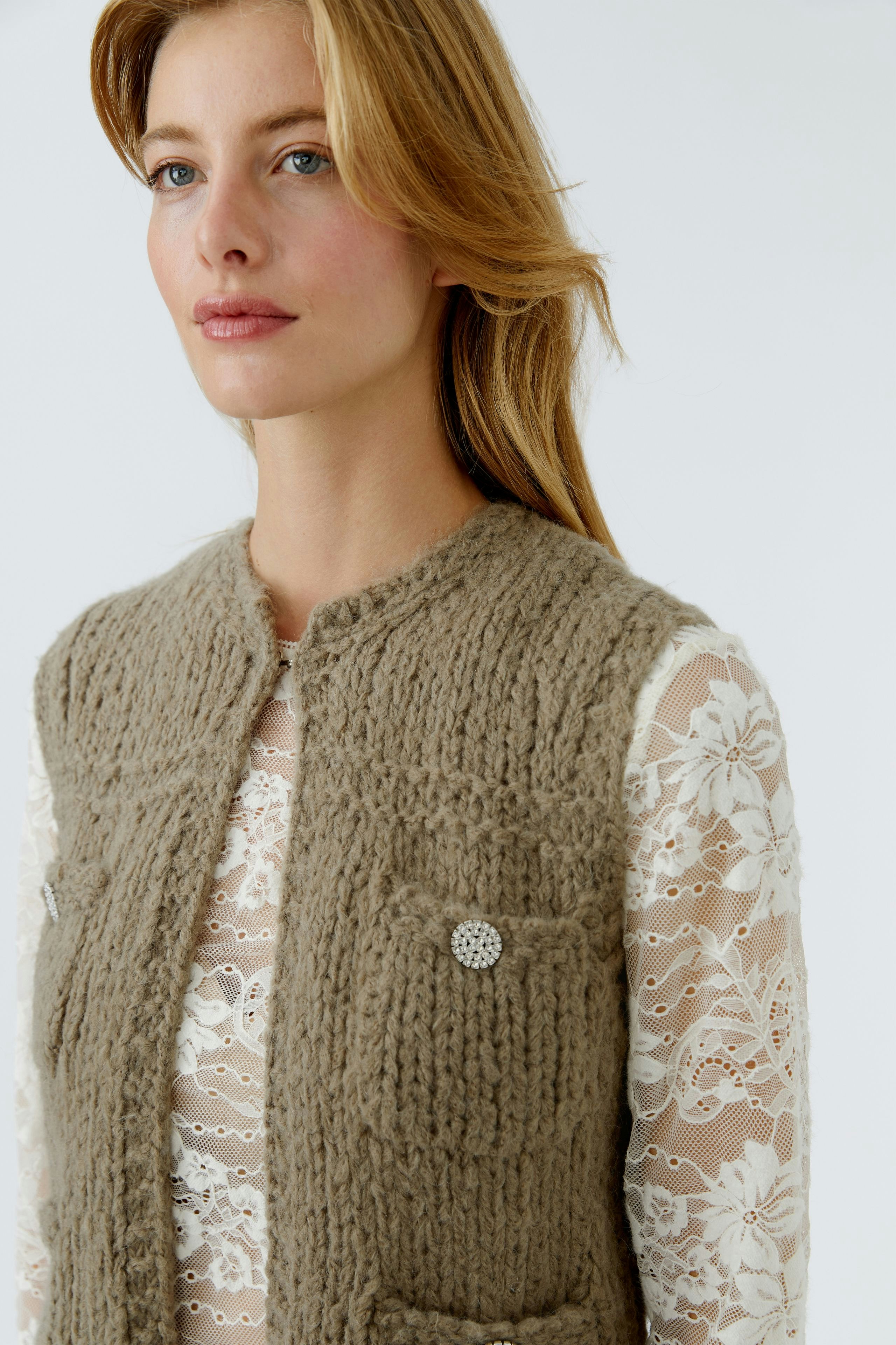 Damen-Strickweste: Frau in beiger Weste mit strukturiertem Material und zwei Taschen.
