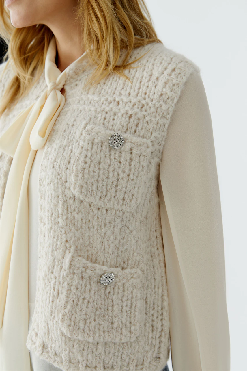 Casual women's cardigan: A woman in a cream knitted cardigan with pockets, styled over a blouse.