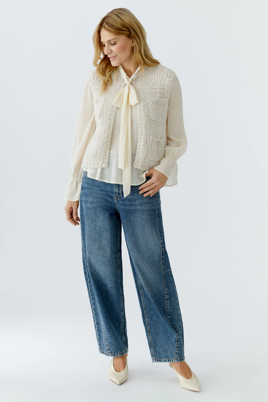 Casual women's cardigan: A woman in a light knitted vest over a blouse and wide jeans, exuding a relaxed vibe.