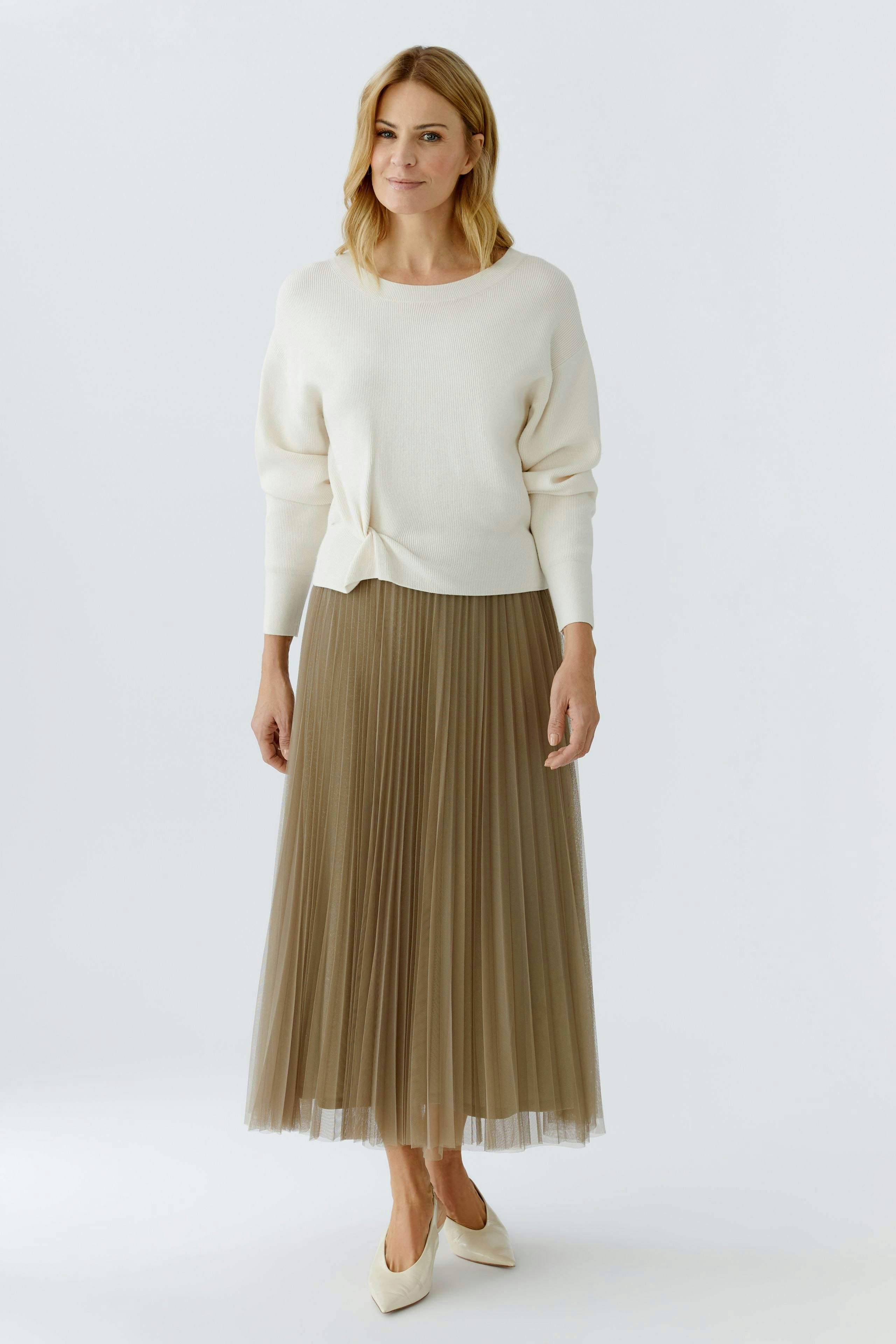 Casual women's pullover: A woman in a cream pullover paired with a pleated skirt, exuding a relaxed vibe.