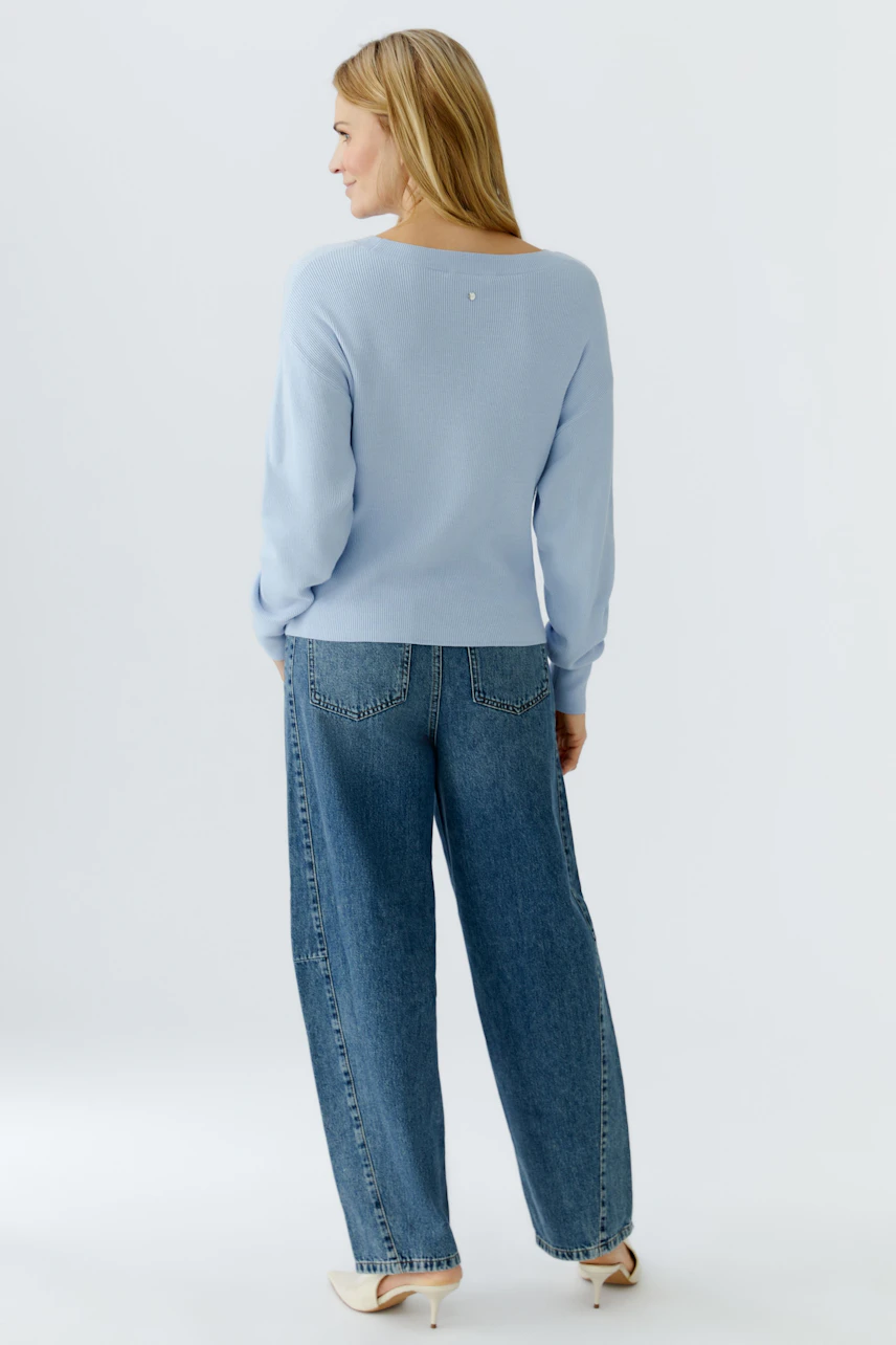 Casual women's pullover: A woman in a light blue pullover paired with wide-leg jeans, showcasing a relaxed style.
