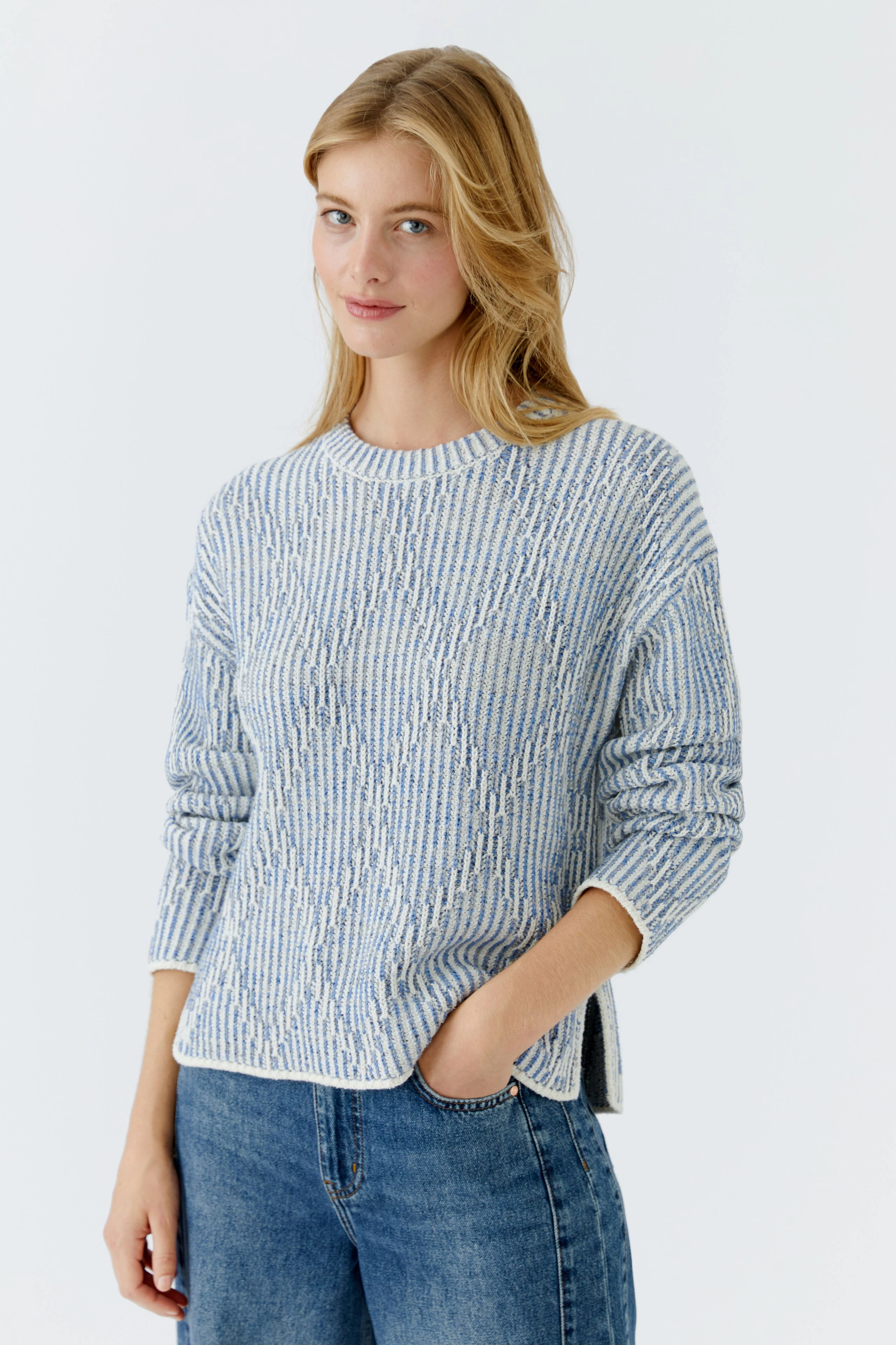 Casual women's pullover: Young woman in a light blue textured pullover with relaxed fit and jeans.