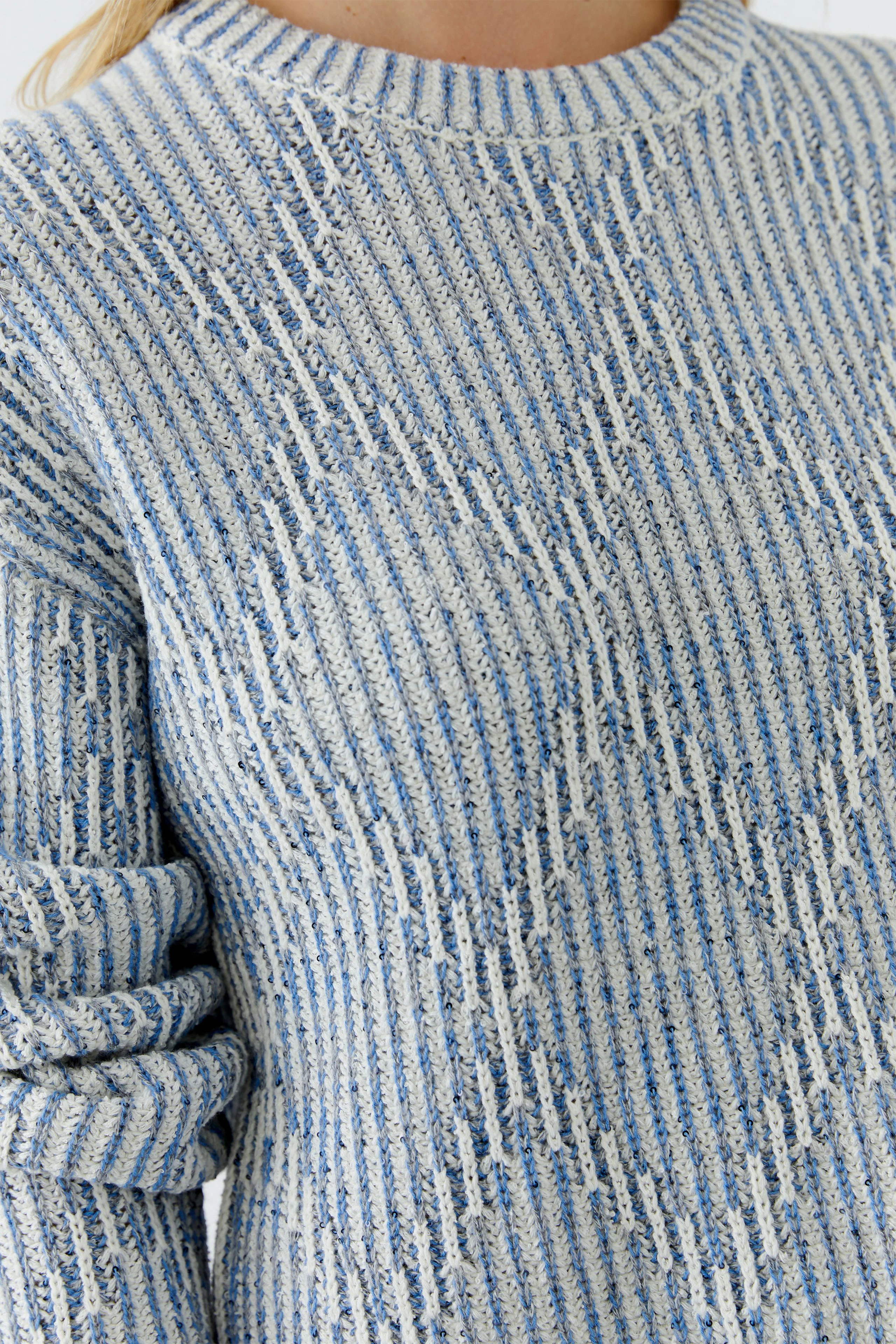 Casual women's pullover: Close-up of a light blue striped pullover with rolled sleeves.