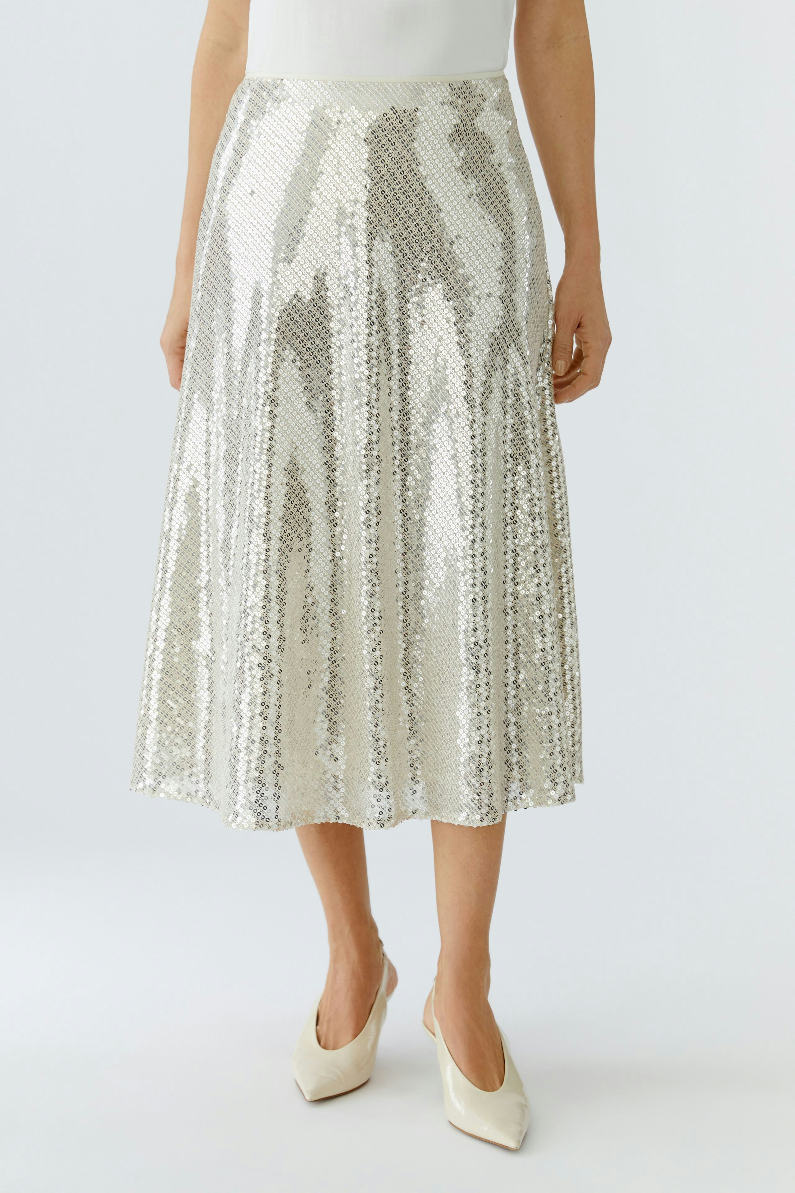 A-Linien-Rock: Frau trägt einen glitzernden Rock in Silber mit schwingendem Schnitt.