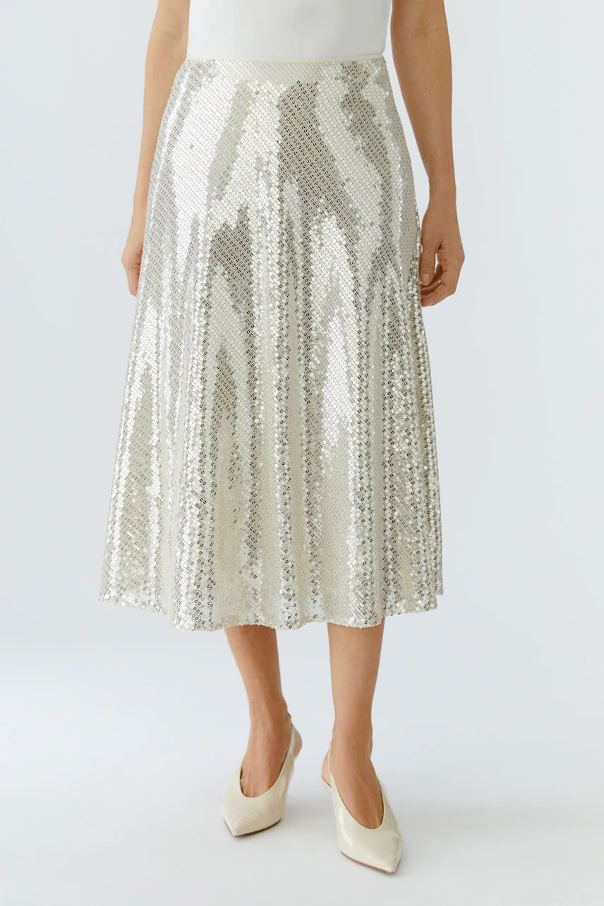 Shiny A-line skirt: Woman in a silver sequined skirt, showcasing a flowing design and stylish look.