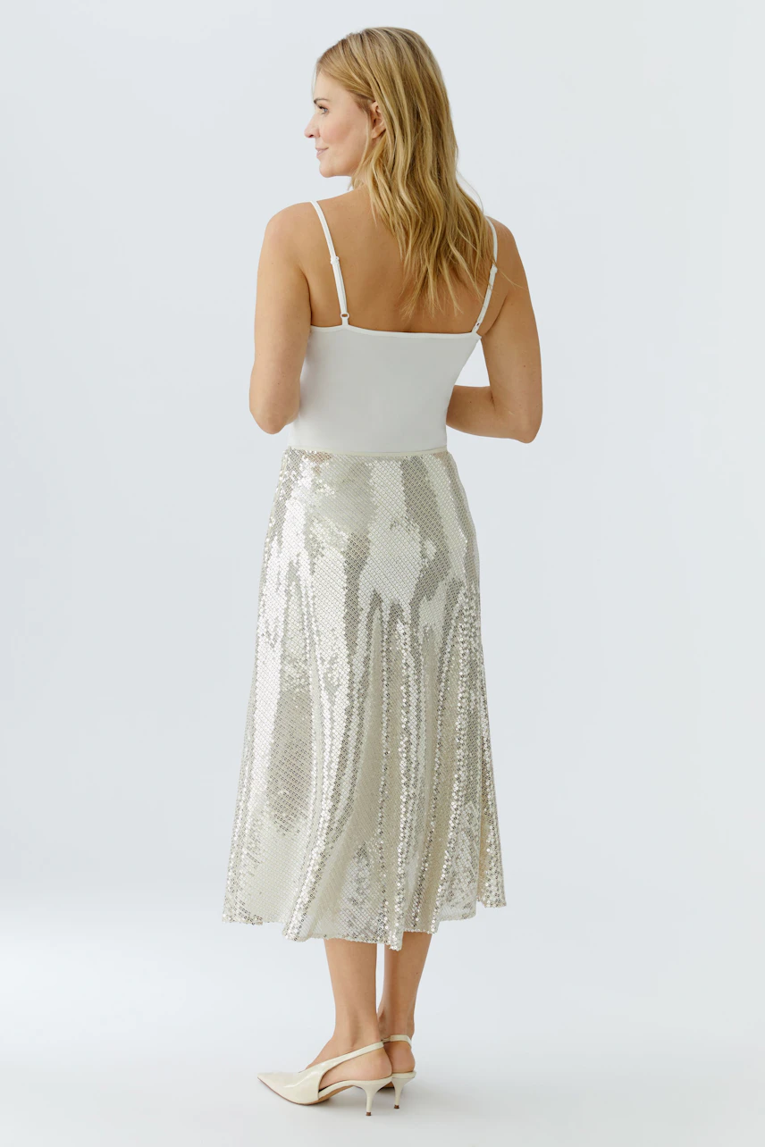 A-line skirt: Woman in a shiny silver skirt with a flowing design, paired with a simple top.
