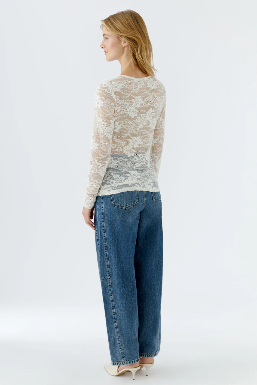 Lightweight long-sleeve shirt: Woman in a sheer lace top paired with relaxed-fit jeans.
