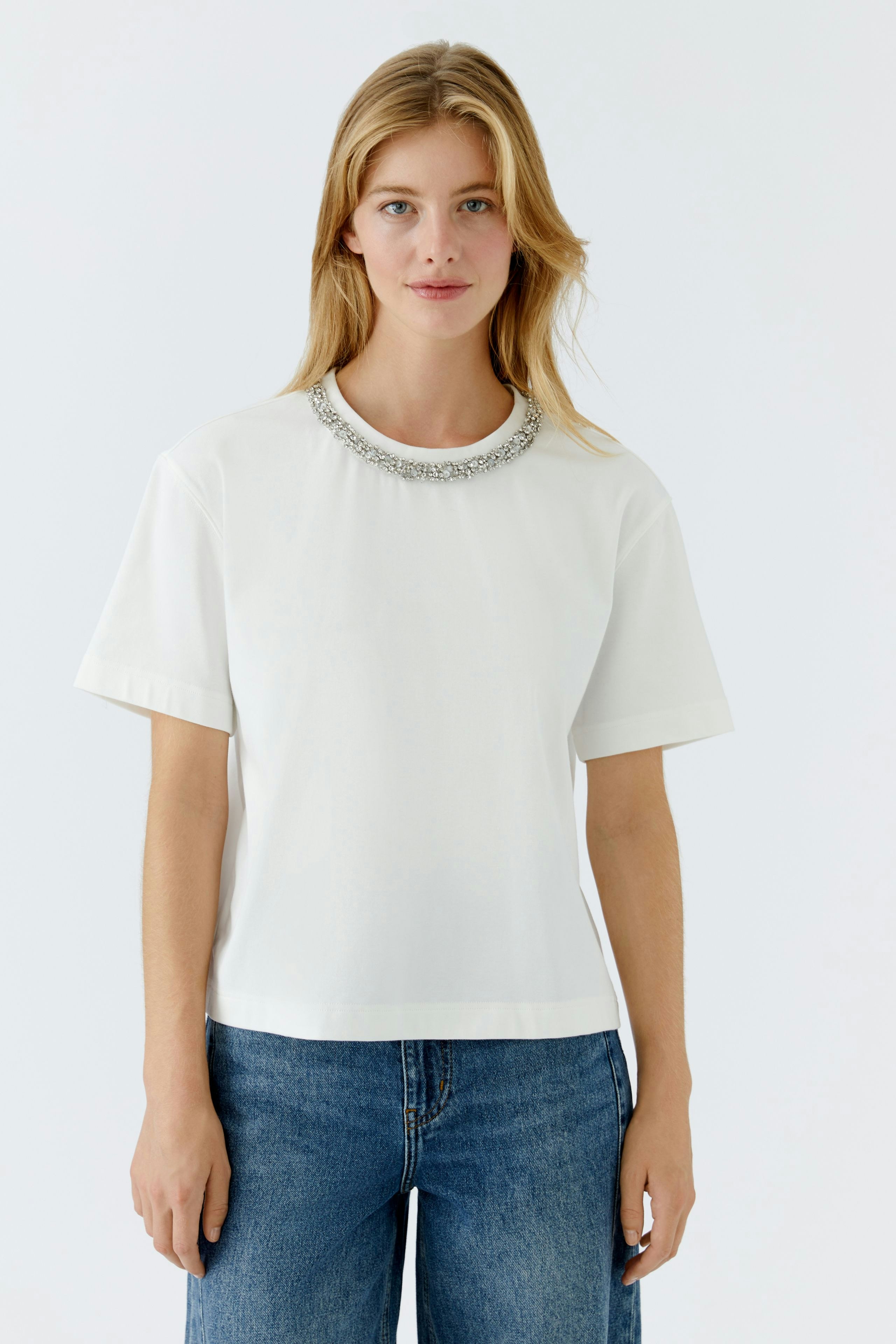 Casual women's T-shirt: Young woman in a white tee with a decorative neckline and relaxed fit.