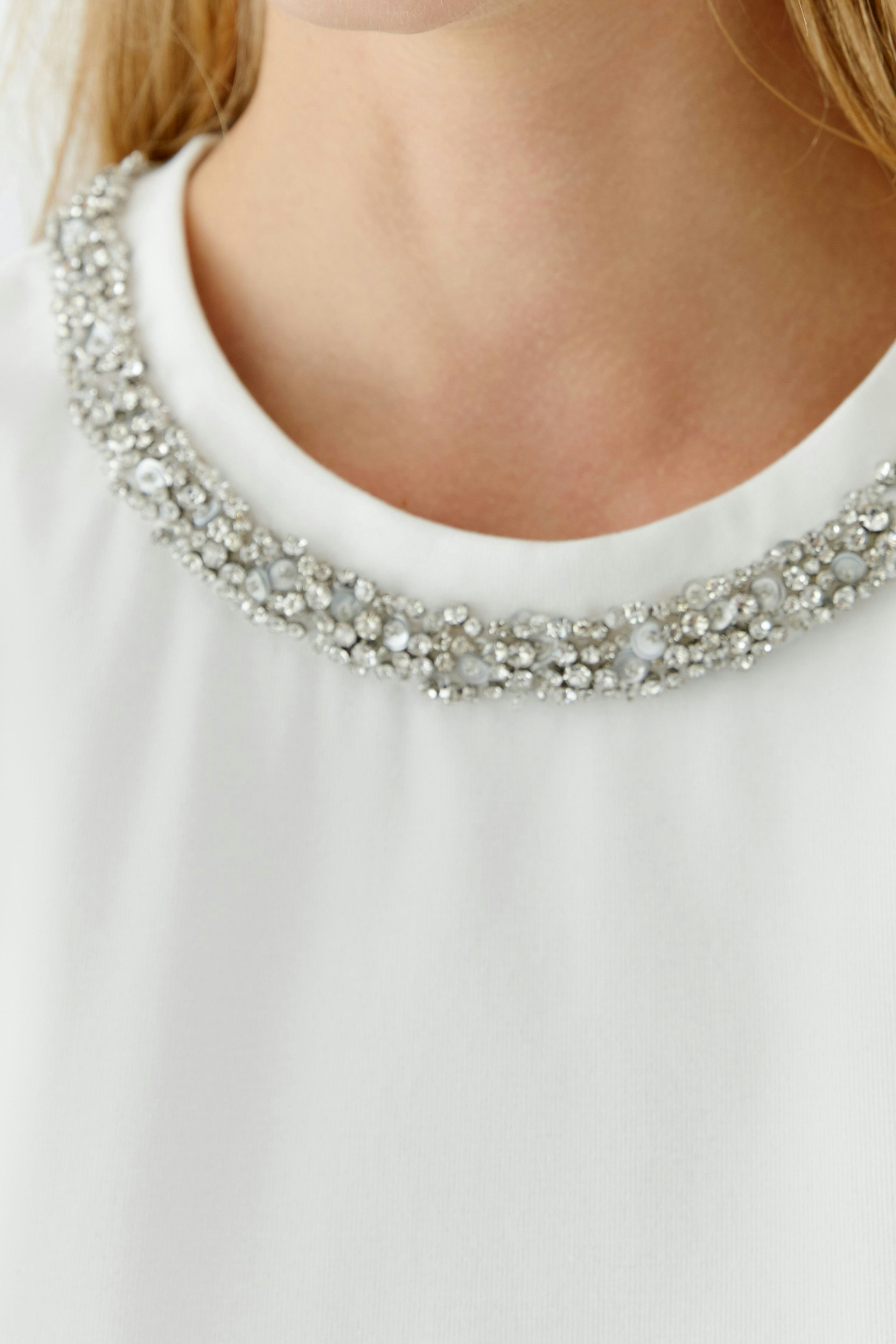 Stylish women's T-shirt with a decorative beaded neckline, perfect for casual wear.