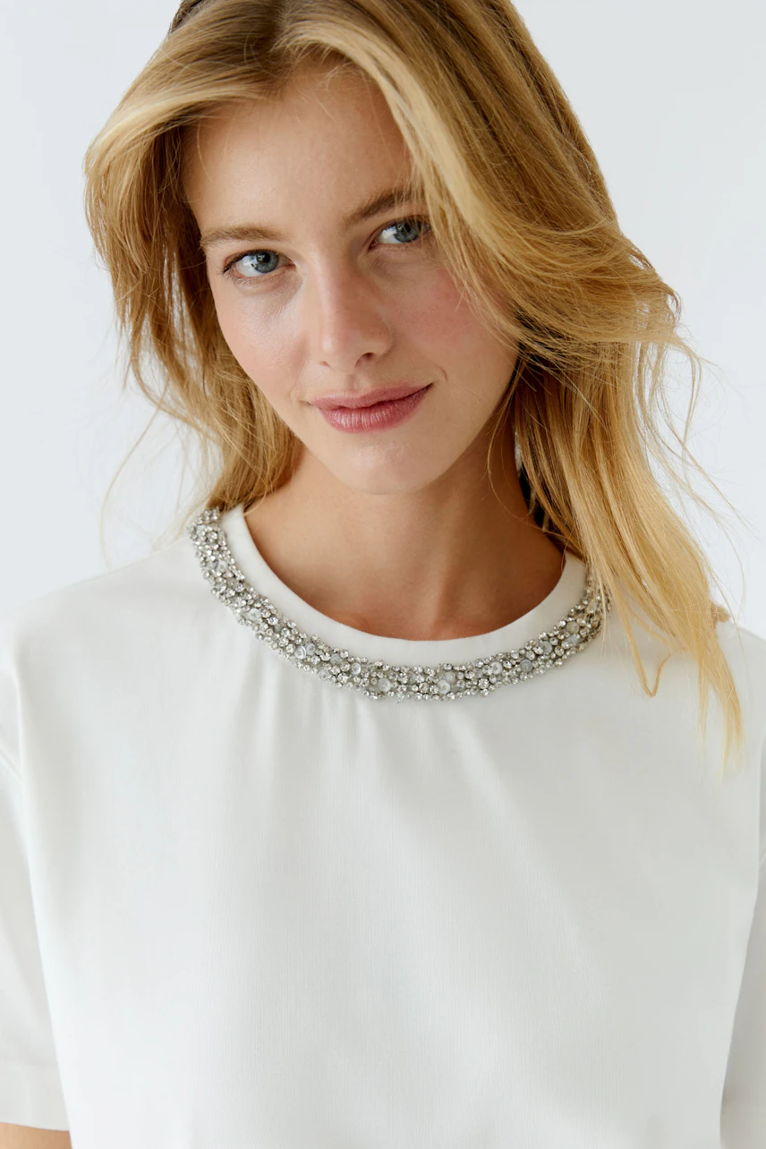 Casual women's T-shirt with a decorative neckline, model smiling at the camera.