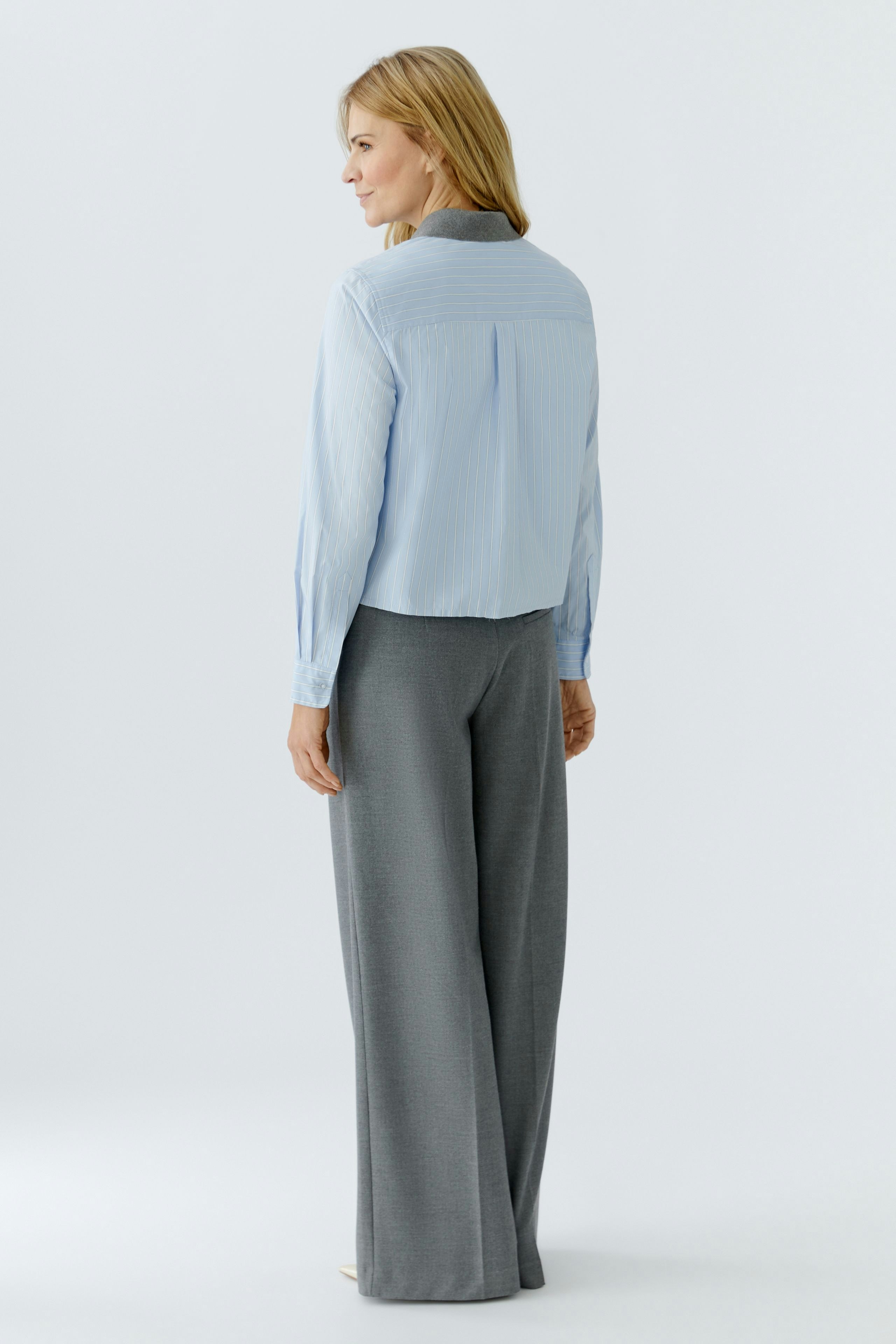 Casual women's blouse: Woman in a light blue striped blouse with a relaxed fit and back detail.