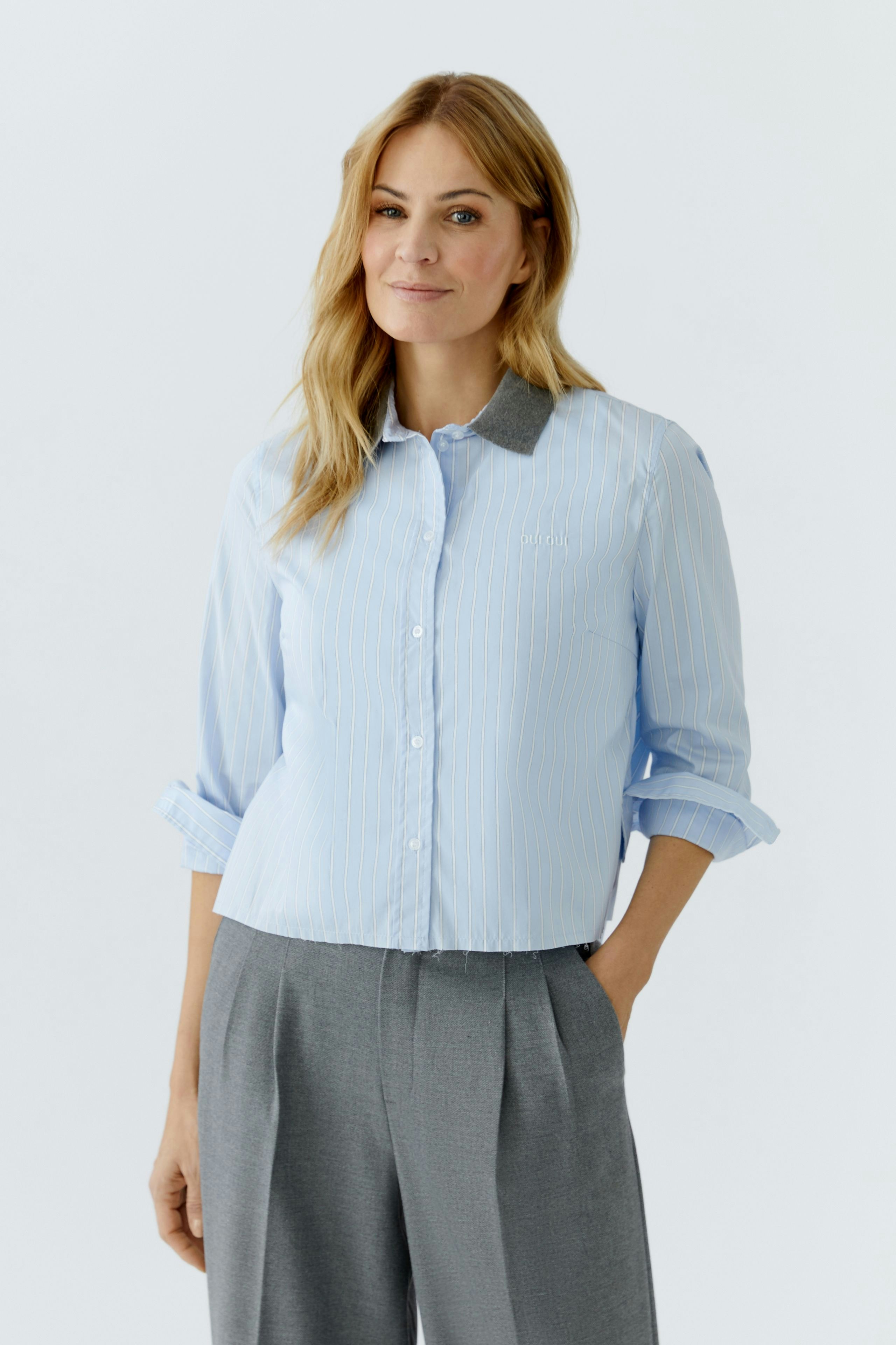 Casual women's blouse: Woman in a light blue striped blouse with rolled sleeves and a contrasting collar.