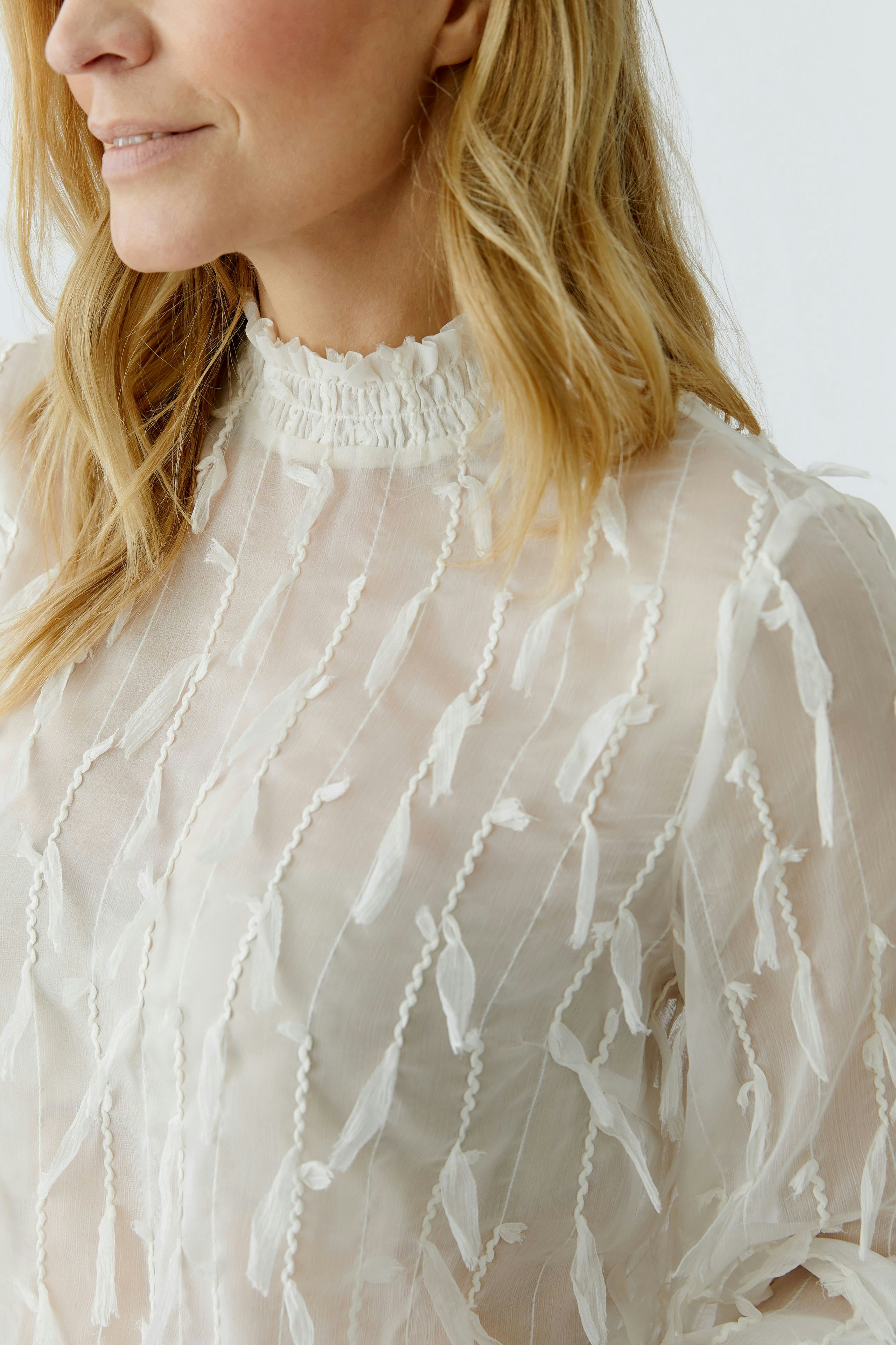 Lightweight women's blouse with textured details, featuring a high neckline and flowing design.