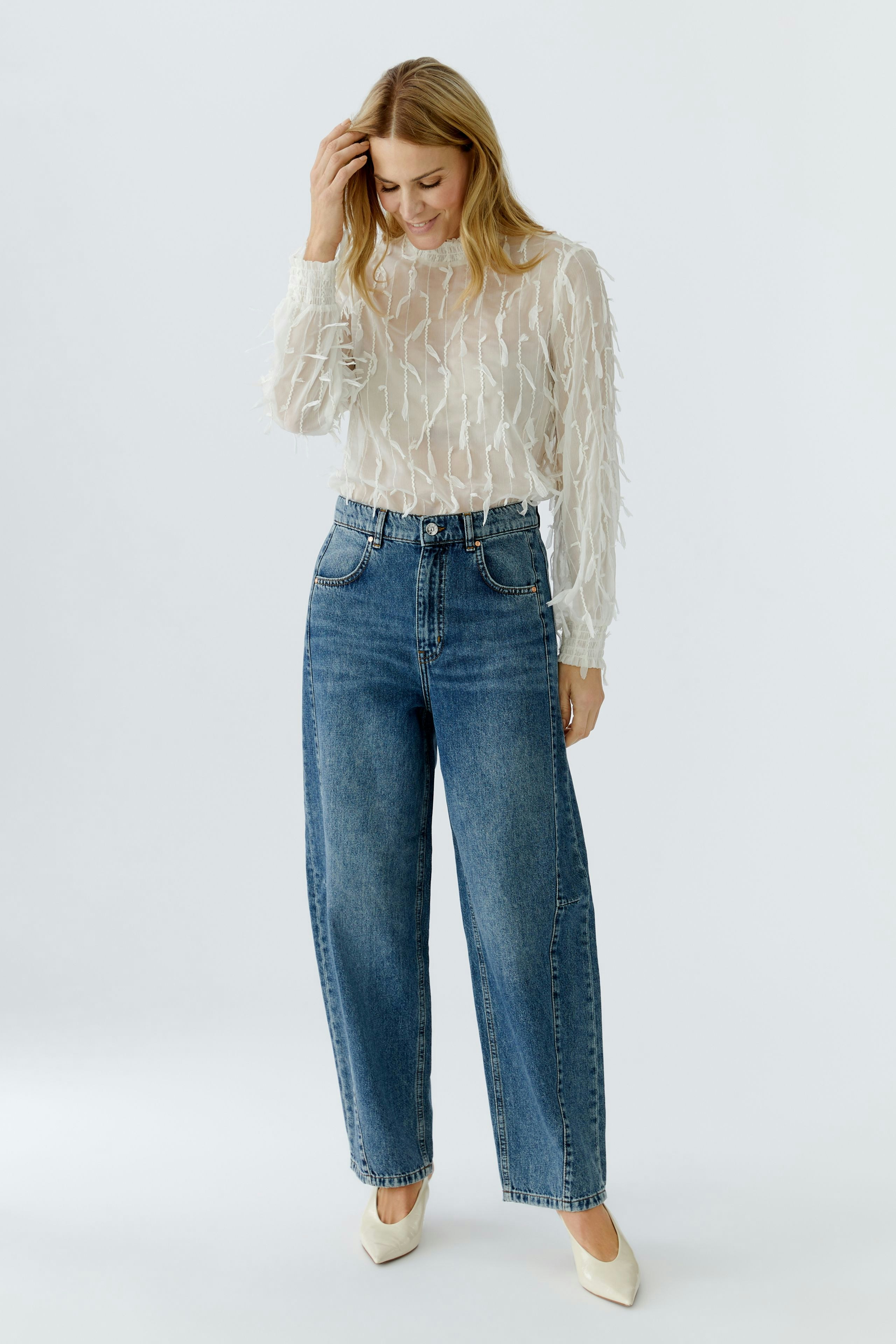 Lightweight women's blouse with textured details, paired with high-waisted jeans.