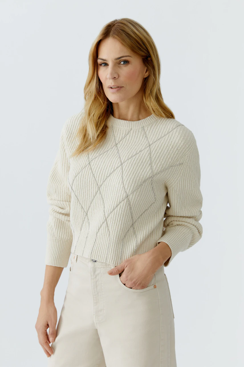 Casual women's pullover: Woman in a cream ribbed pullover with diamond pattern, looking confidently.