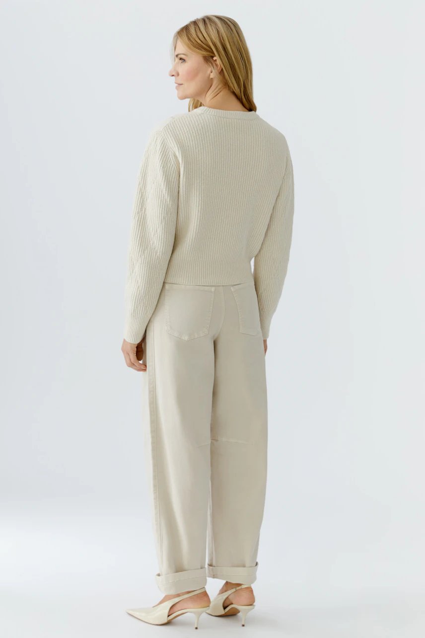 Casual women's pullover: A woman in a light beige textured pullover and relaxed-fit pants.
