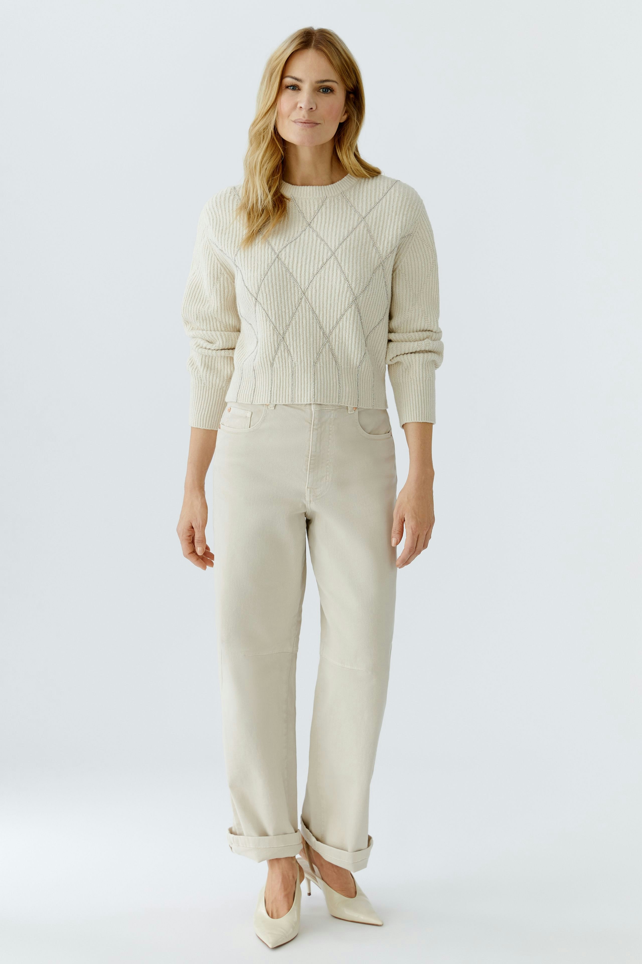 Casual women's pullover: A woman in a cream-colored knitted pullover with a diamond pattern.
