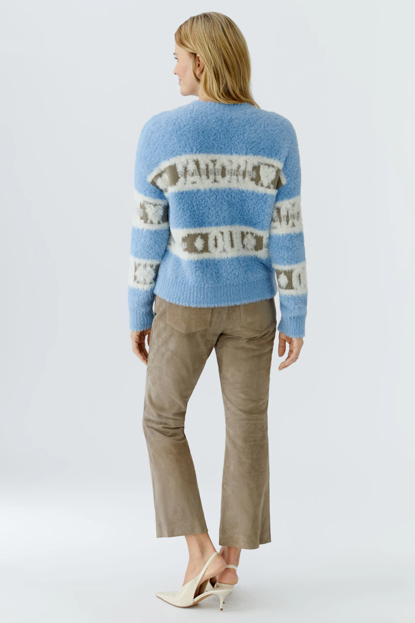 Casual women's pullover: A woman in a blue striped pullover with a relaxed fit, paired with light pants.