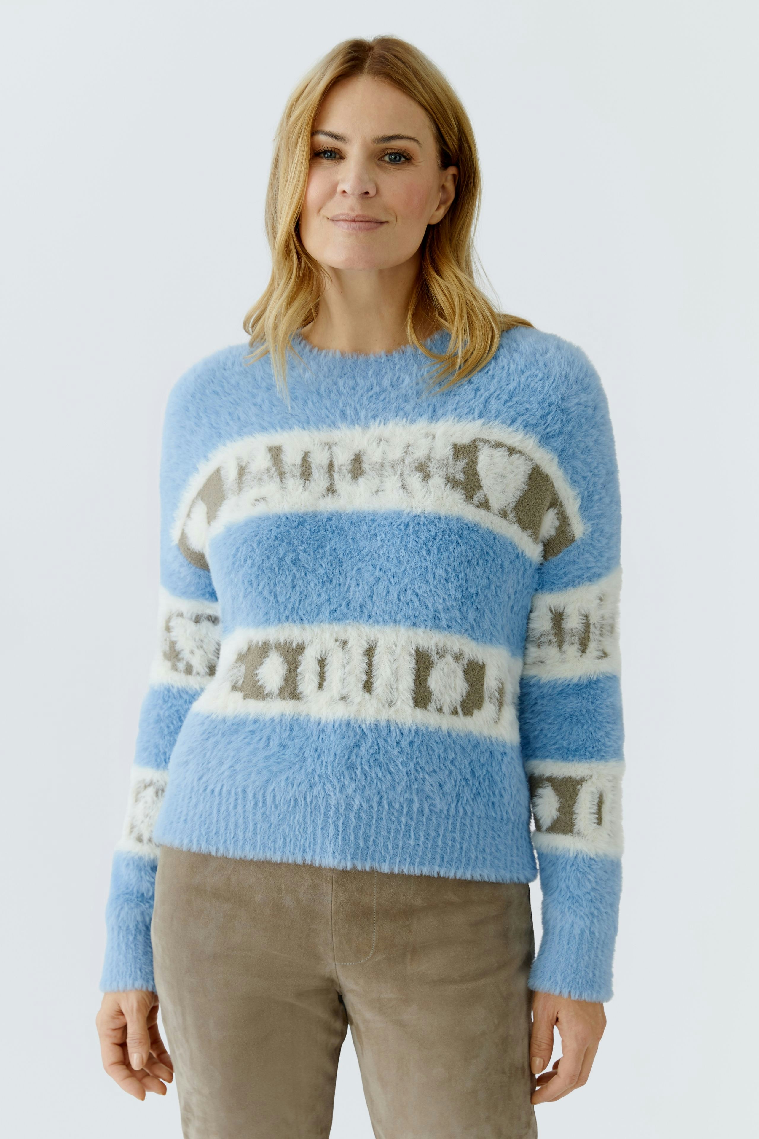 Casual women's pullover: Woman in a fluffy blue pullover with white and beige stripes, smiling confidently.