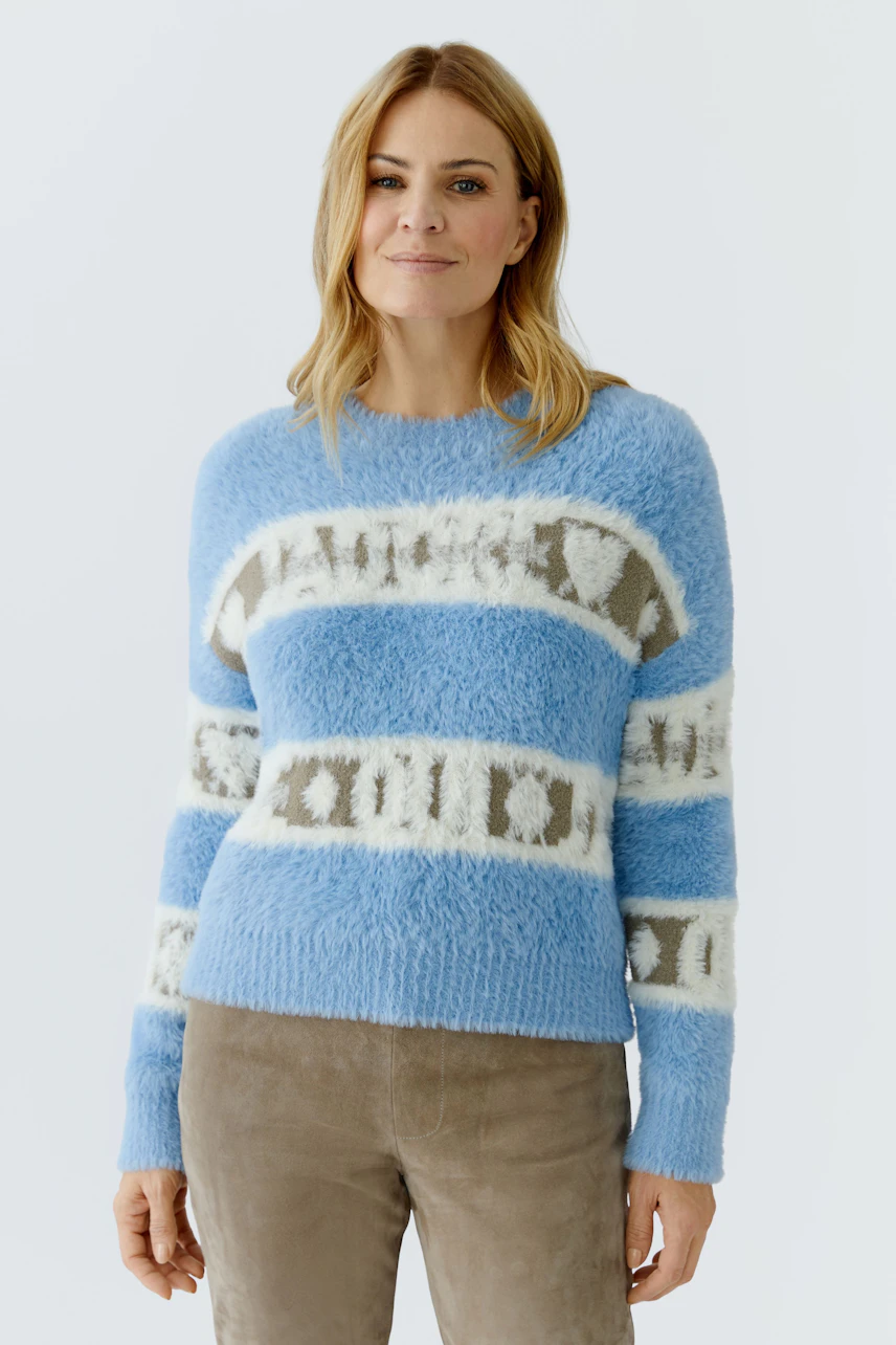 Casual women's pullover: Woman in a fluffy blue pullover with white and beige stripes, smiling confidently.