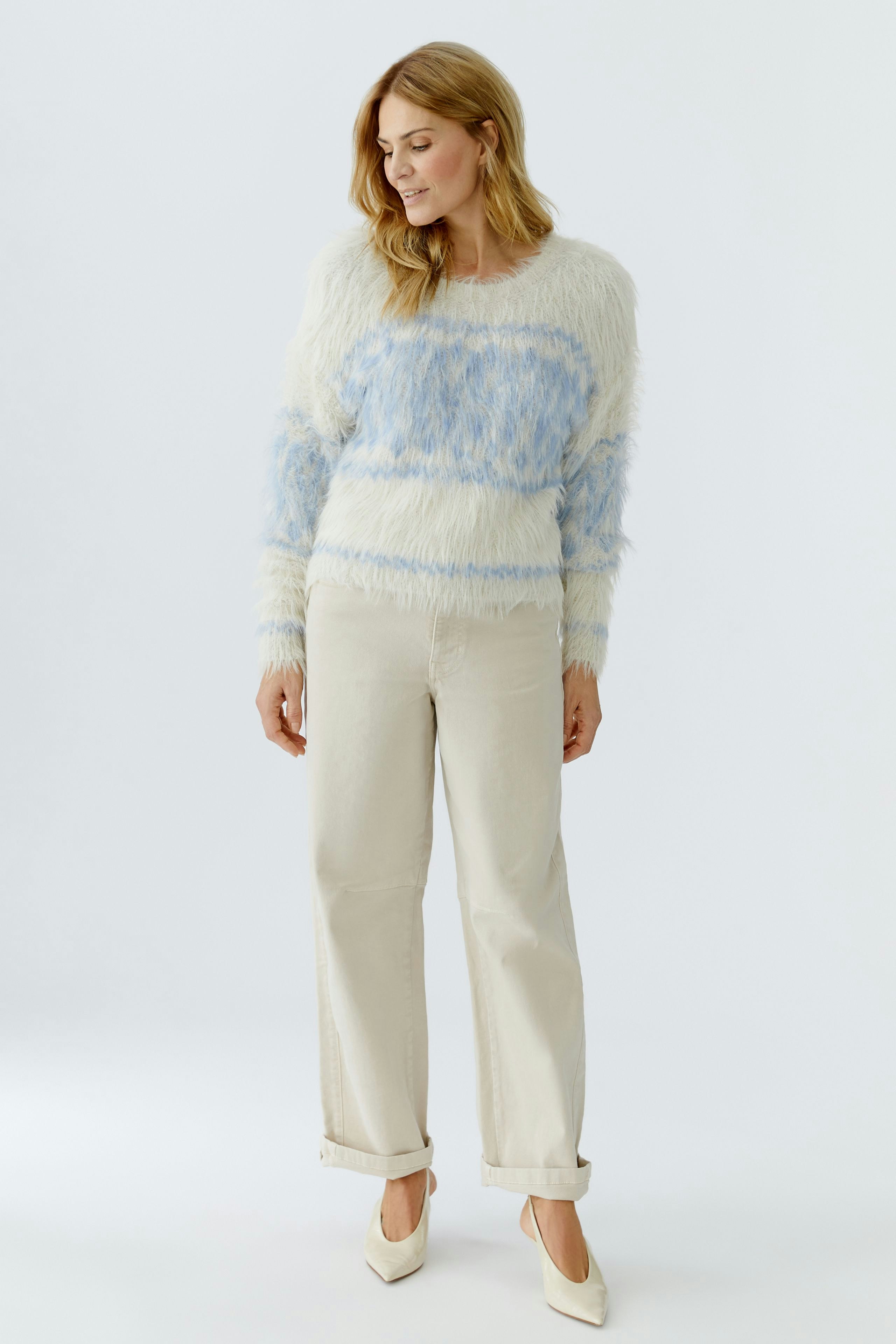 Casual women's pullover: Woman in a fluffy blue and white striped pullover paired with light pants.