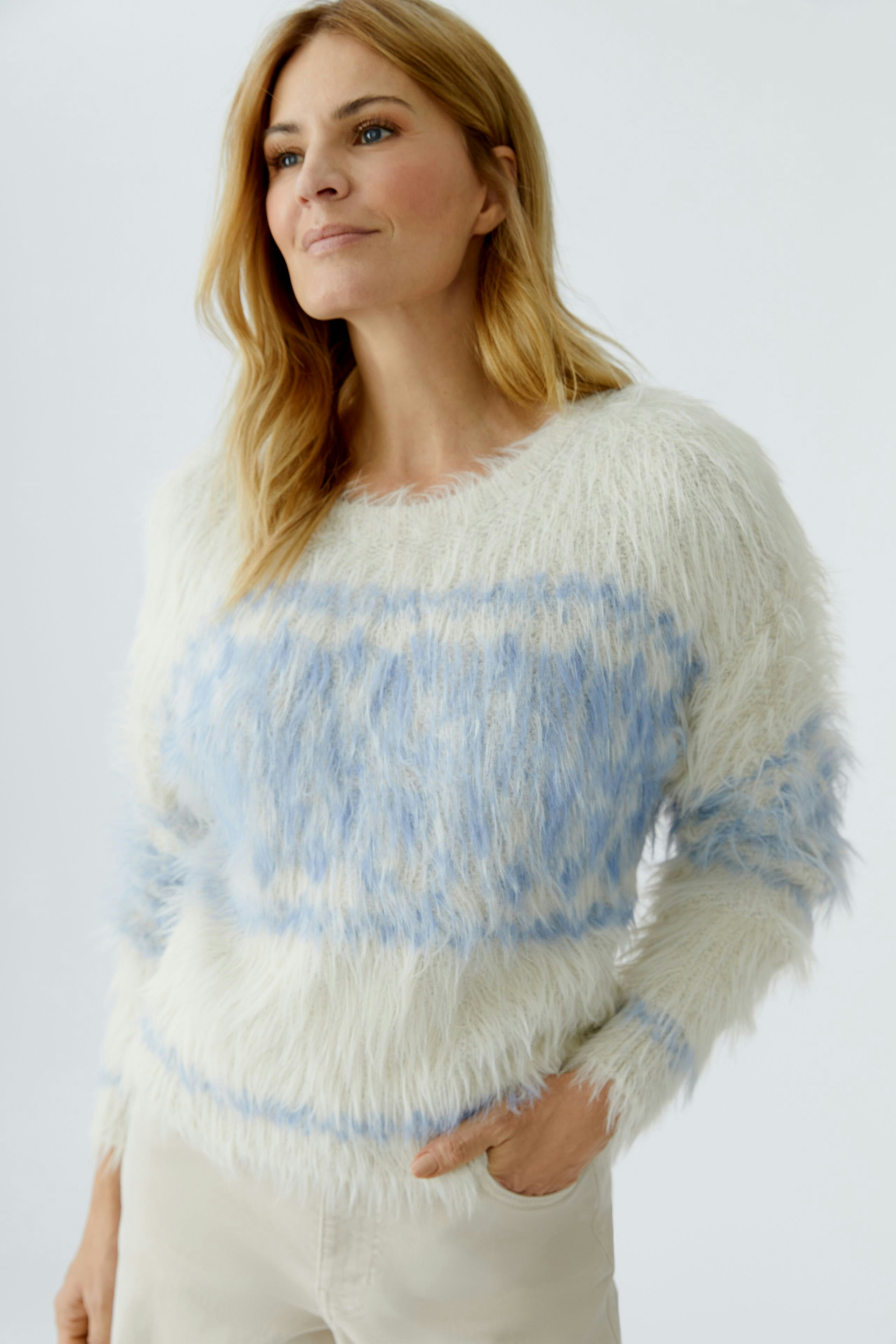 Cozy women's pullover: Woman in fluffy white and blue striped pullover, looking relaxed.