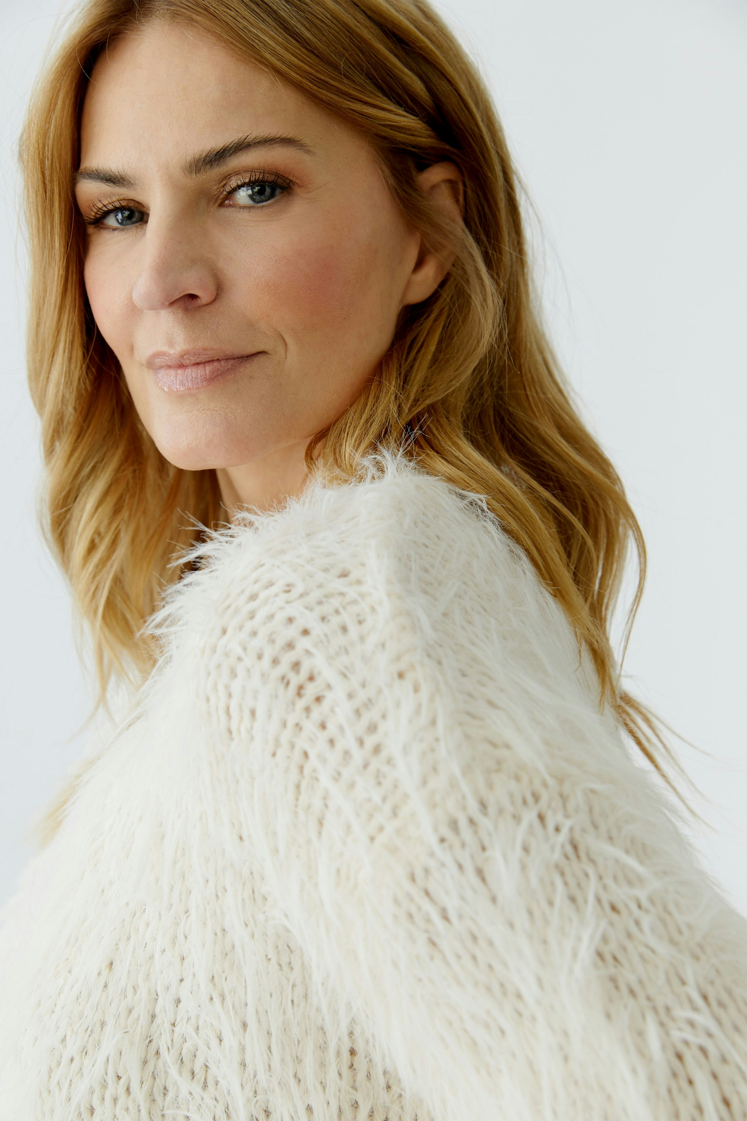 Casual women's pullover: A woman in a fluffy white pullover with a relaxed fit looks confidently at the camera.