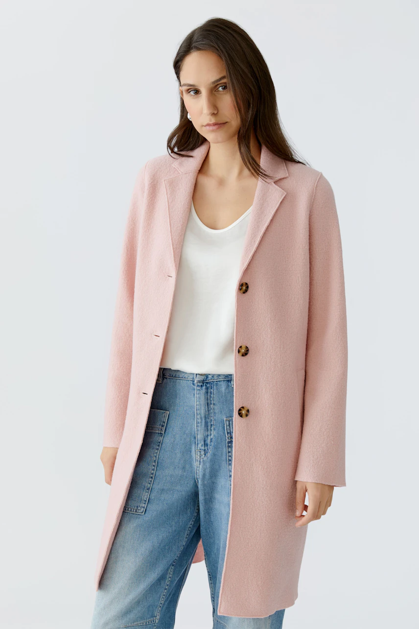 Modern women's wool coat: A woman in a light pink coat with buttons, paired with casual jeans.