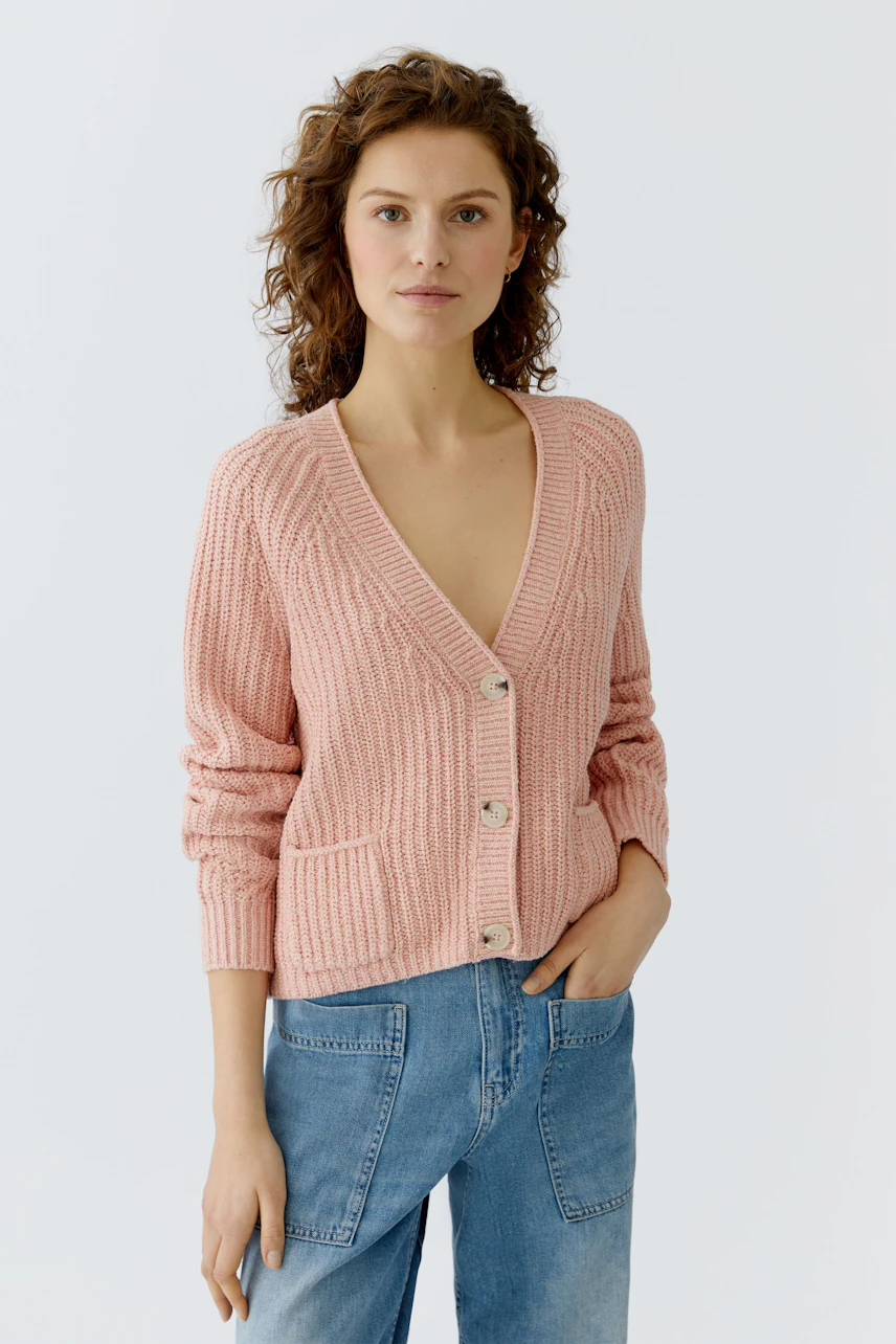 Casual women's cardigan: A woman in a pink knitted cardigan with buttons and pockets, paired with jeans.