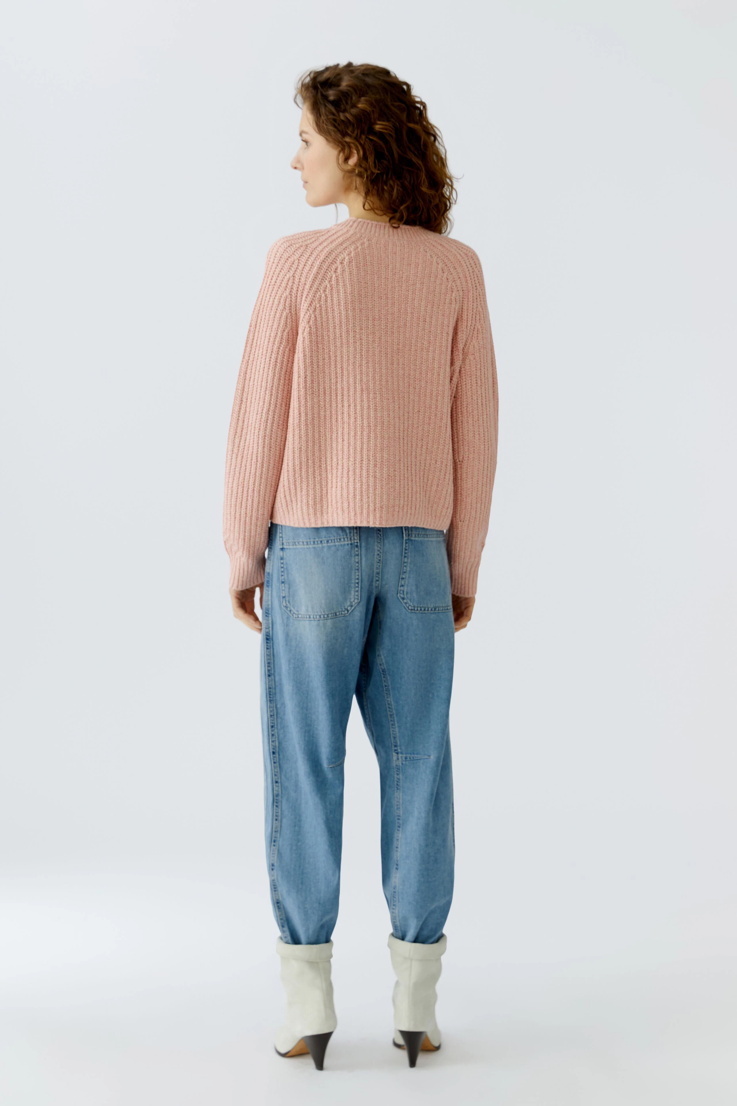 Casual women's cardigan: A woman in a pink ribbed cardigan paired with relaxed-fit jeans.