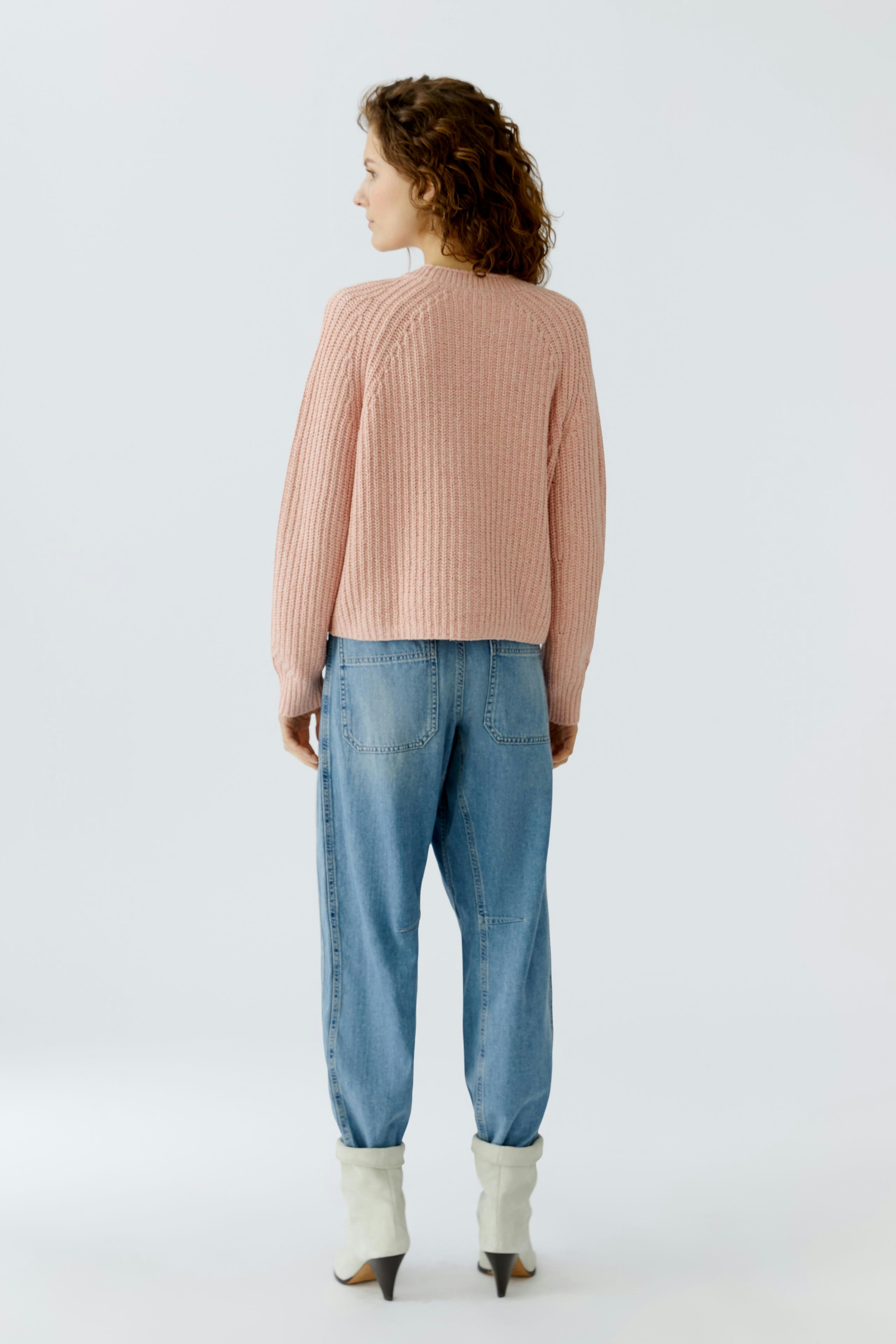 Casual women's cardigan: A woman in a pink ribbed cardigan paired with relaxed-fit jeans.