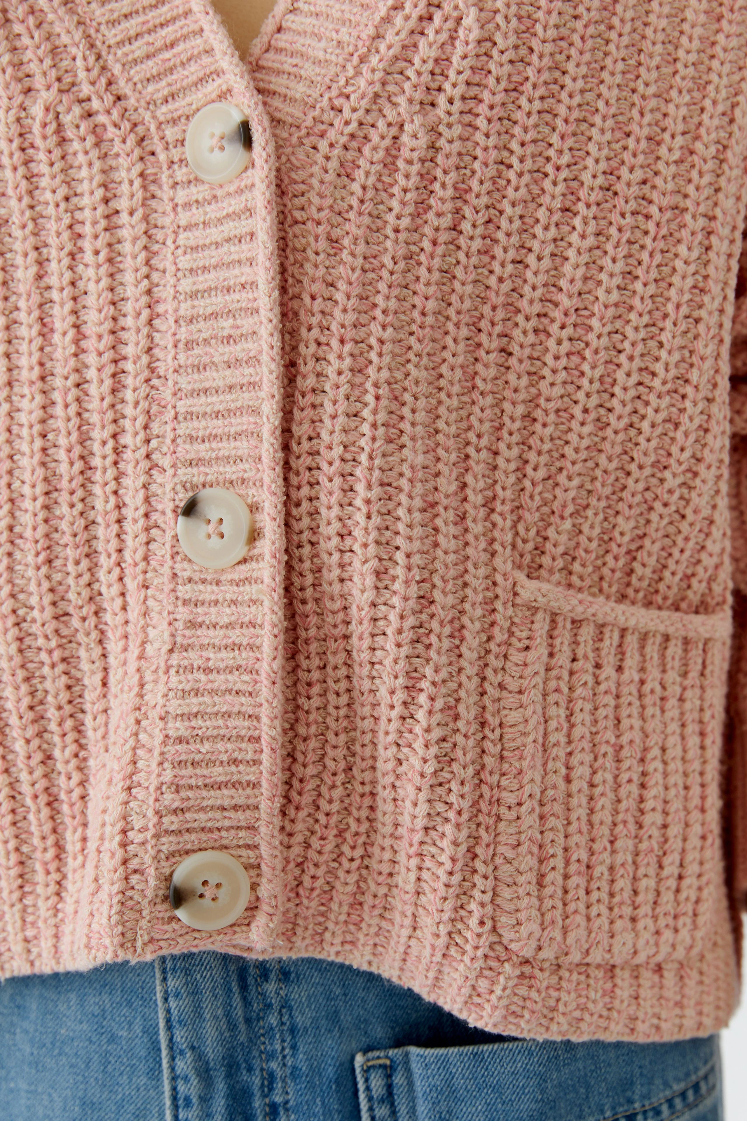 Casual women's cardigan: Close-up of a pink knitted cardigan with buttons and a pocket.