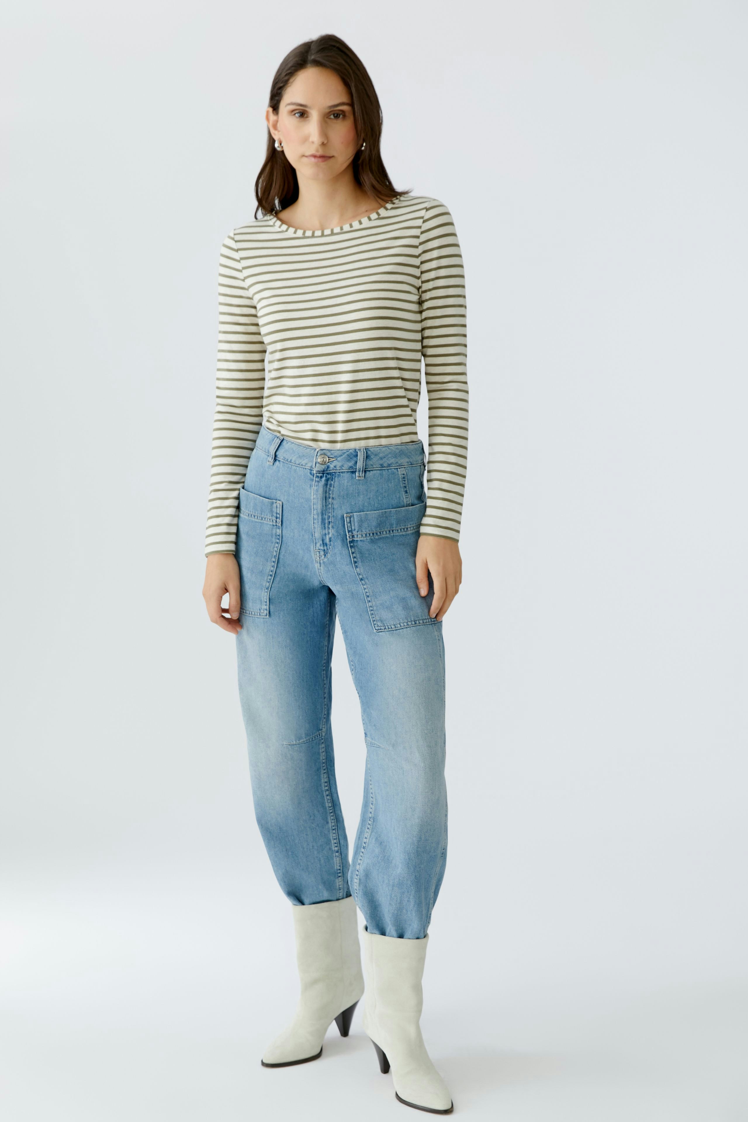 Langarmshirt: Junge Frau in gestreiftem Langarmshirt und lässigen Jeans steht selbstbewusst.