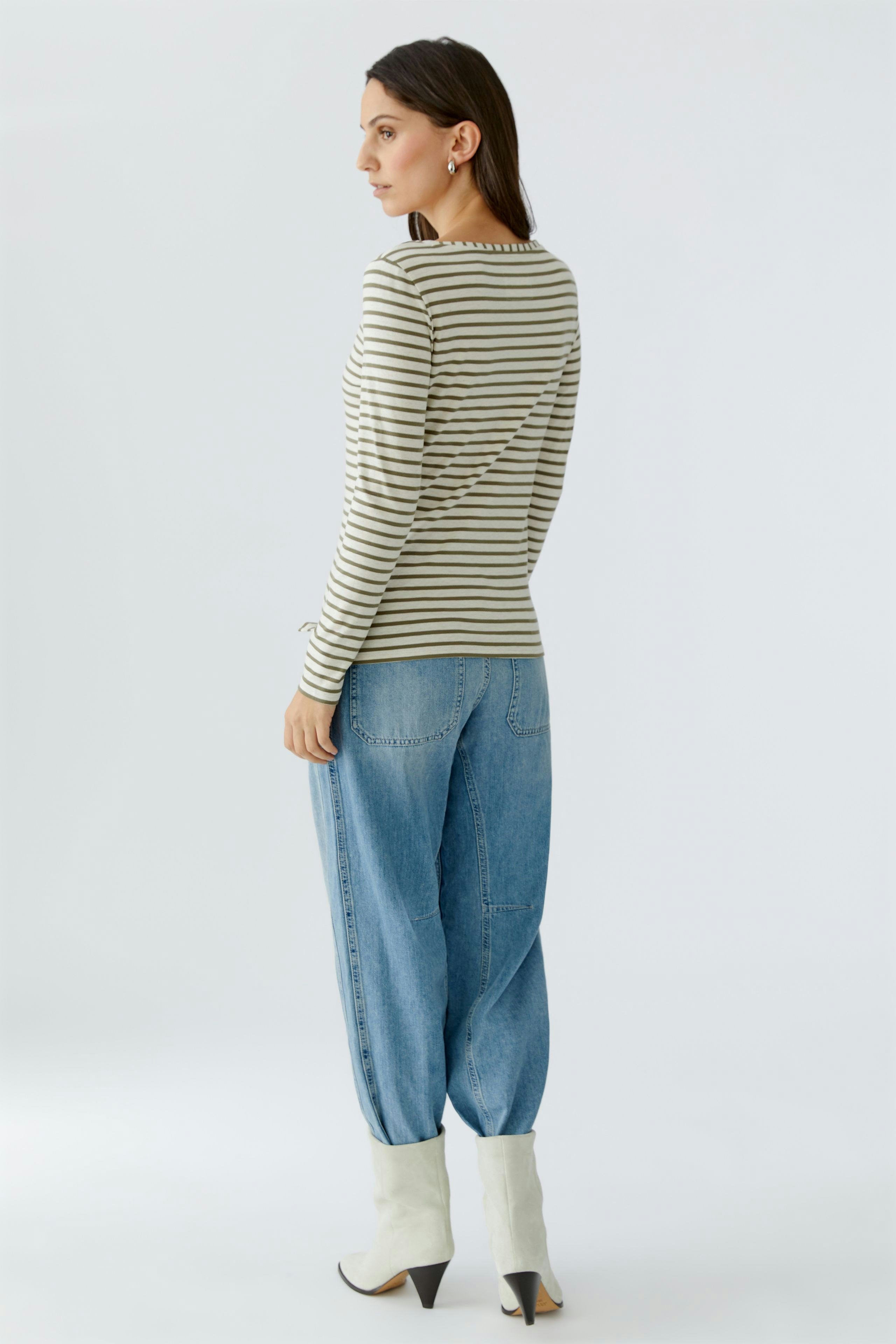 Striped long-sleeve shirt: Woman in a fitted shirt with stripes, paired with relaxed jeans and stylish boots.