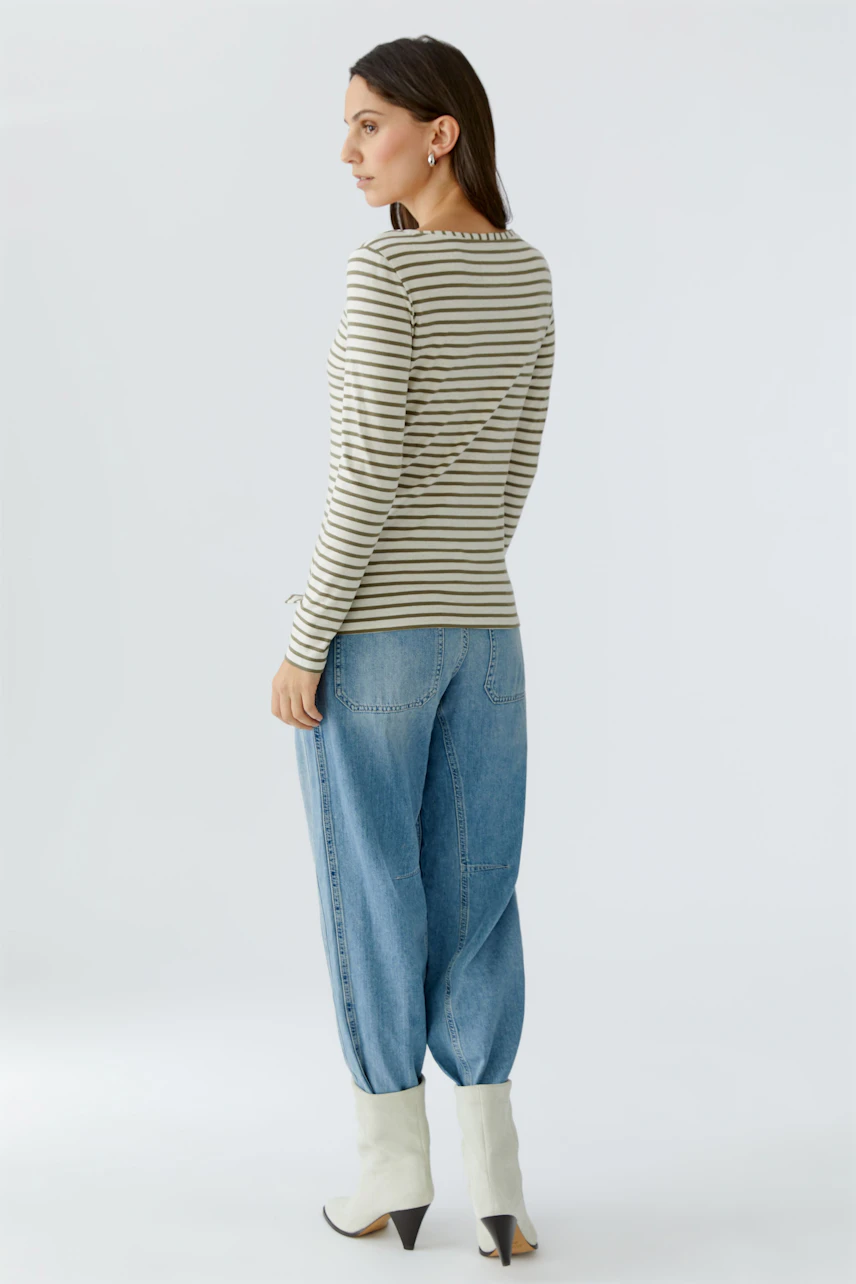 Striped long-sleeve shirt: Woman in a fitted shirt with stripes, paired with relaxed jeans and stylish boots.