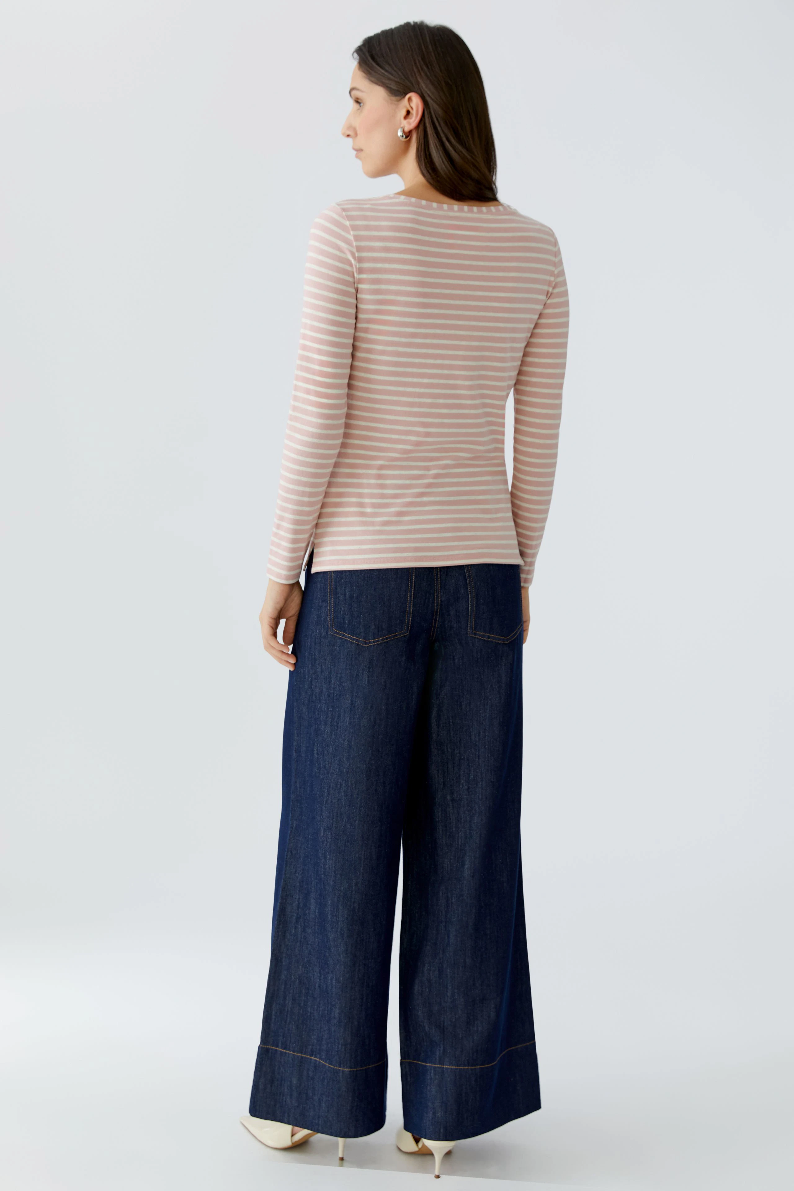 Casual long-sleeve shirt: Woman in a striped pullover paired with wide-leg jeans, showcasing a relaxed style.