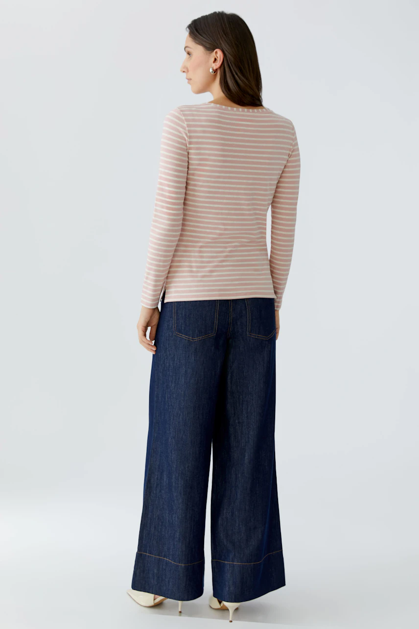 Casual long-sleeve shirt: Woman in a striped pullover paired with wide-leg jeans, showcasing a relaxed style.