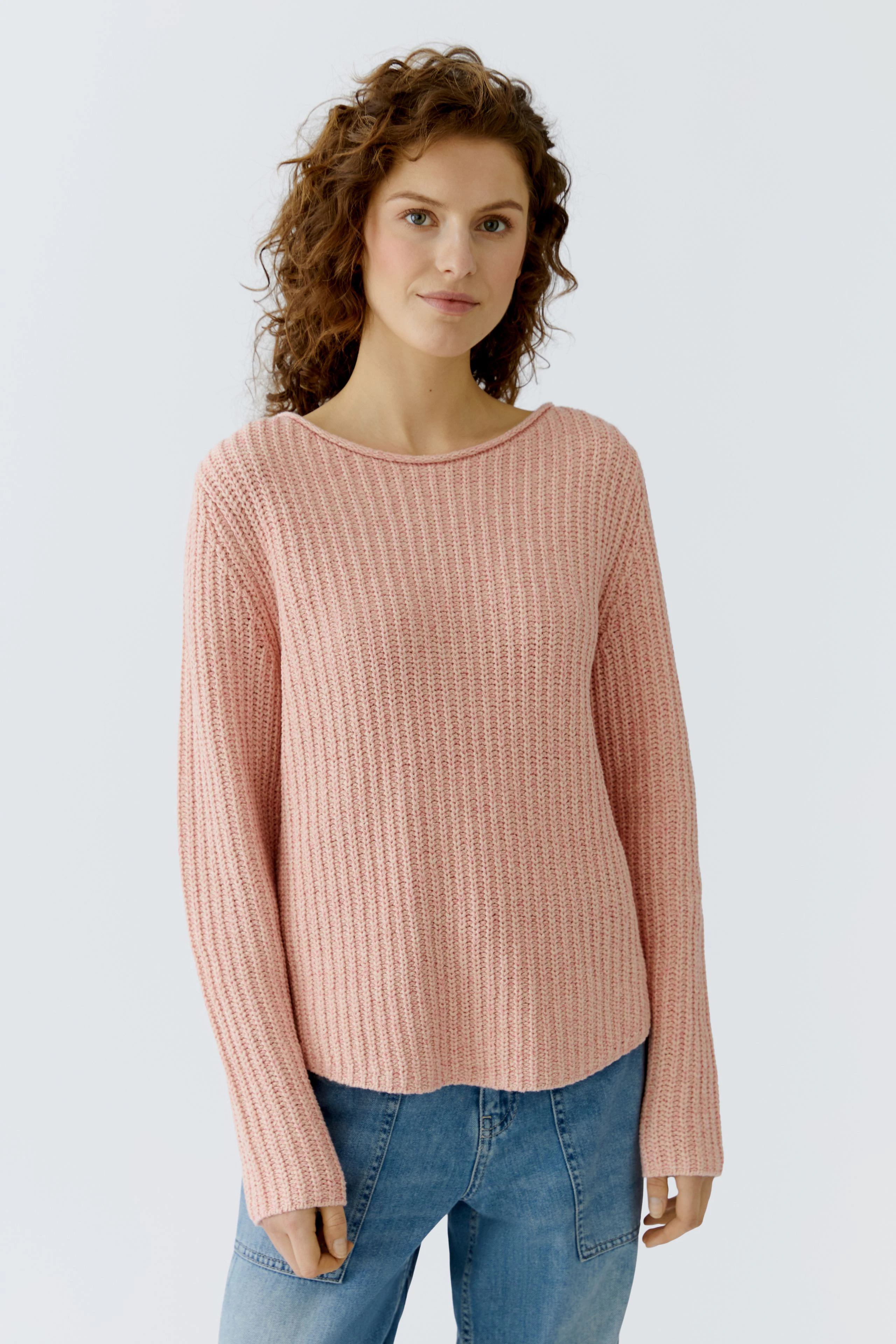 Casual women's pullover: Young woman in a pink textured pullover paired with blue jeans.