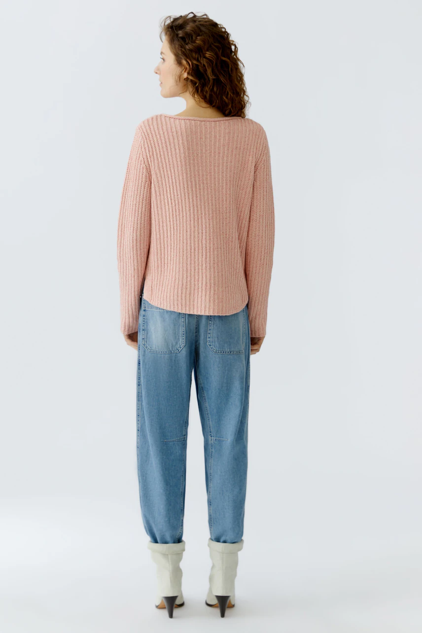 Casual women's pullover: A woman in a soft pink ribbed pullover paired with relaxed denim pants.