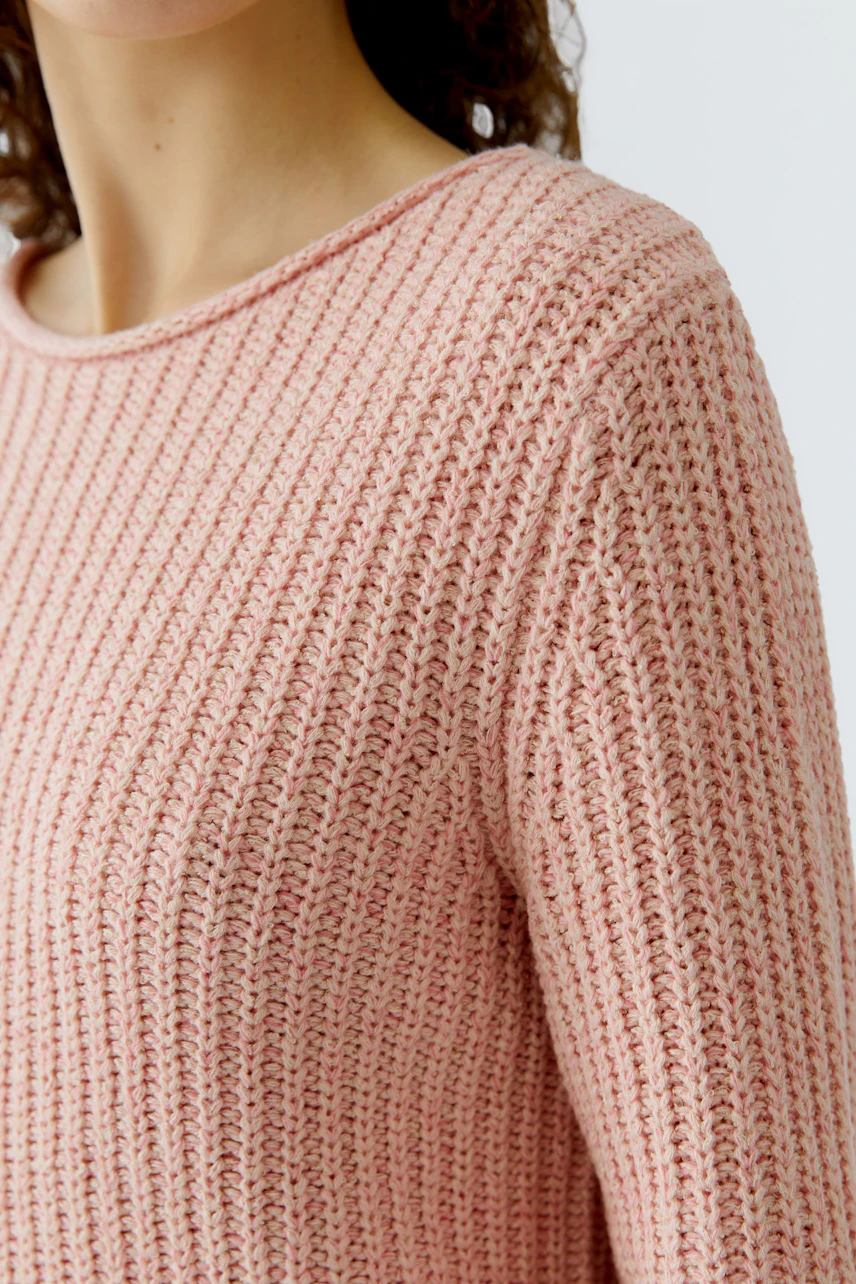 Casual women's pullover: Close-up of a woman in a light pink textured pullover with a relaxed fit.