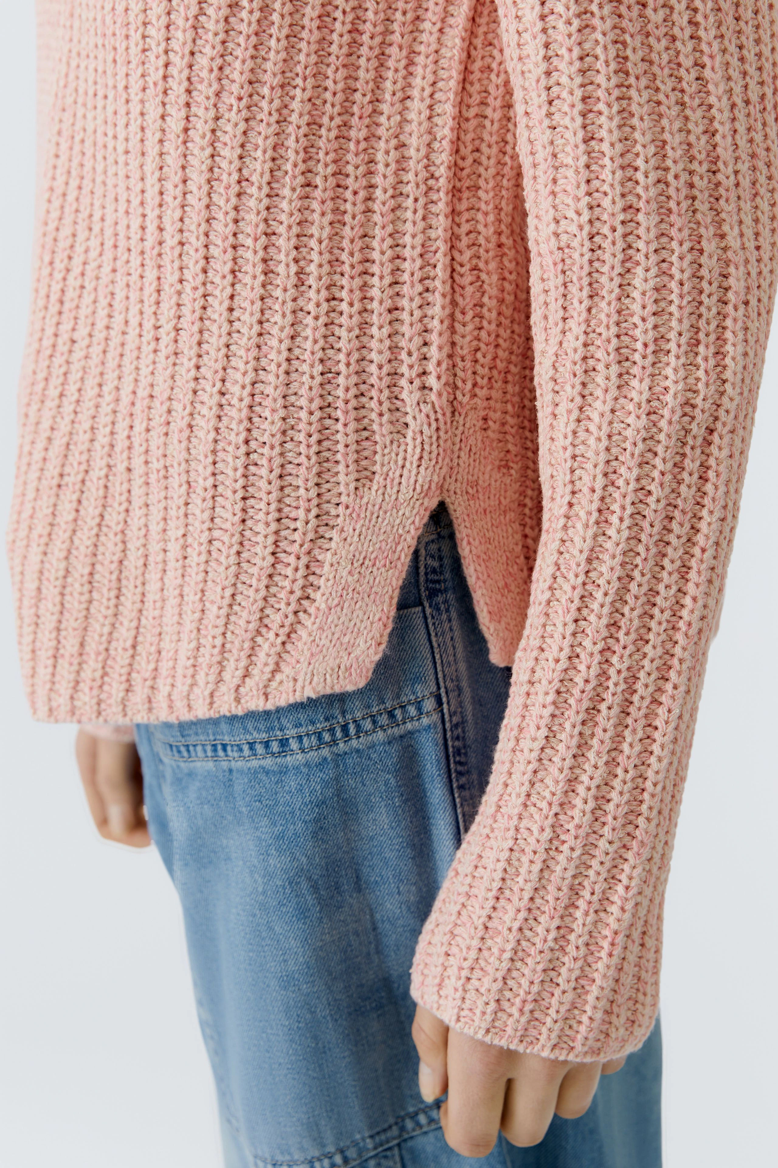 Casual women's pullover in soft pink with a textured knit, paired with denim jeans.