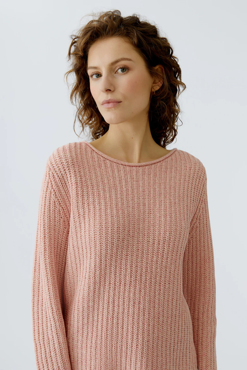 Casual women's pullover: A woman in a soft pink knit pullover with a relaxed fit.