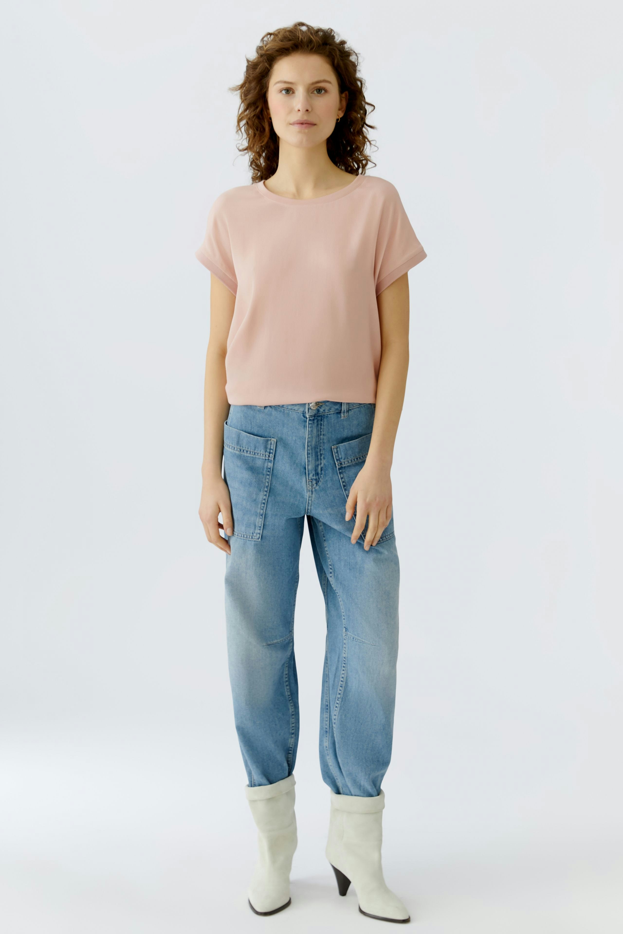 Casual women's blouse shirt: A woman in a light pink blouse paired with relaxed-fit jeans.