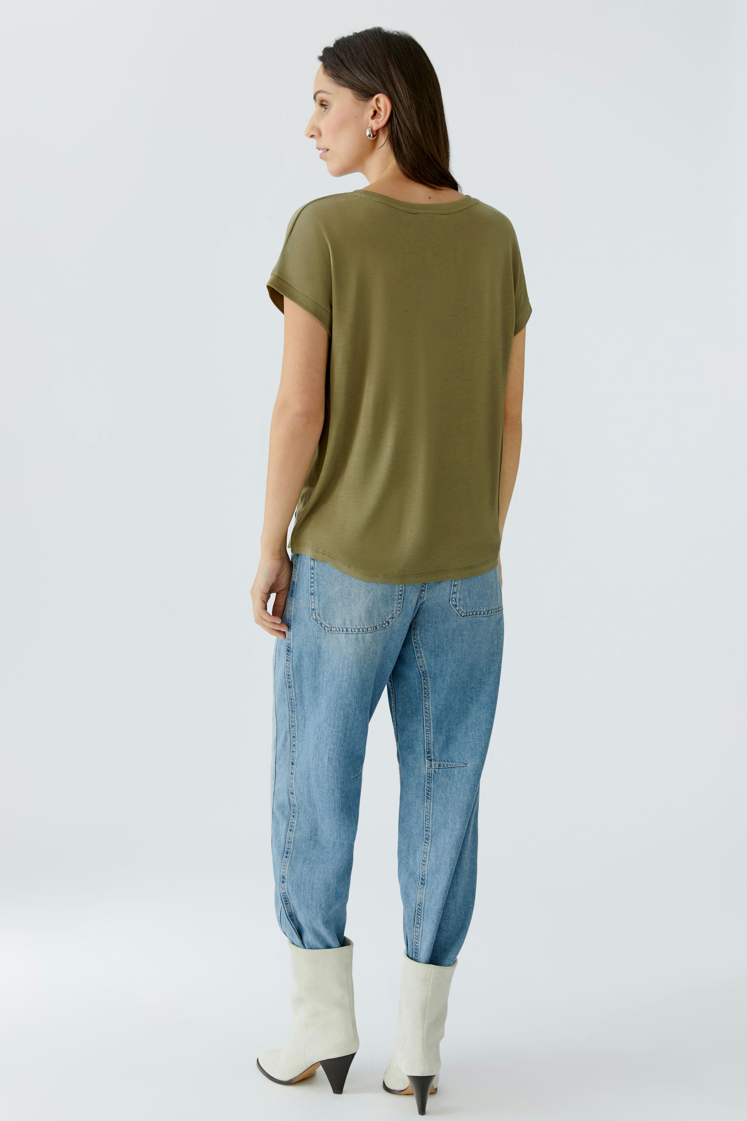 Casual women's blouse shirt: A woman in an olive green top paired with relaxed-fit jeans.