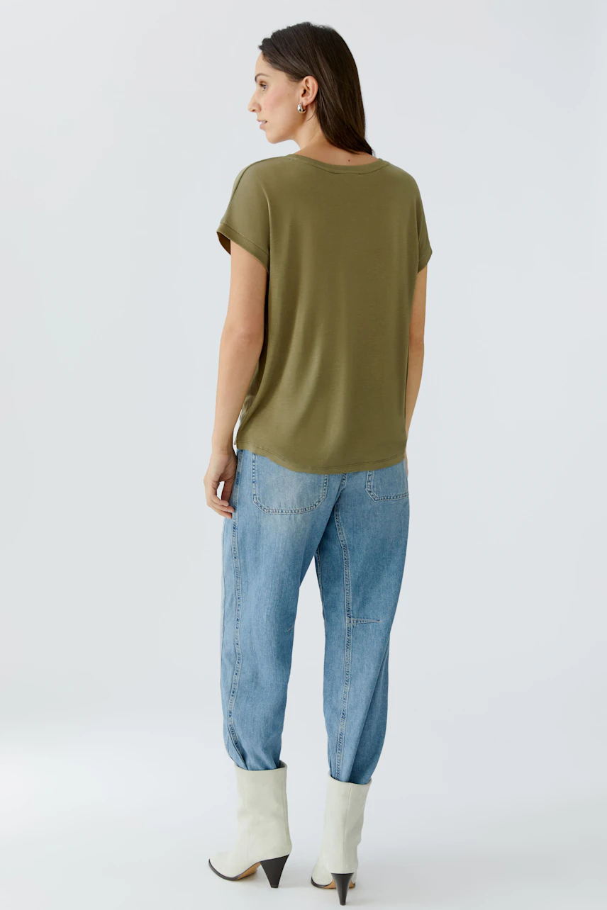 Casual women's blouse shirt: A woman in an olive green top paired with relaxed-fit jeans.